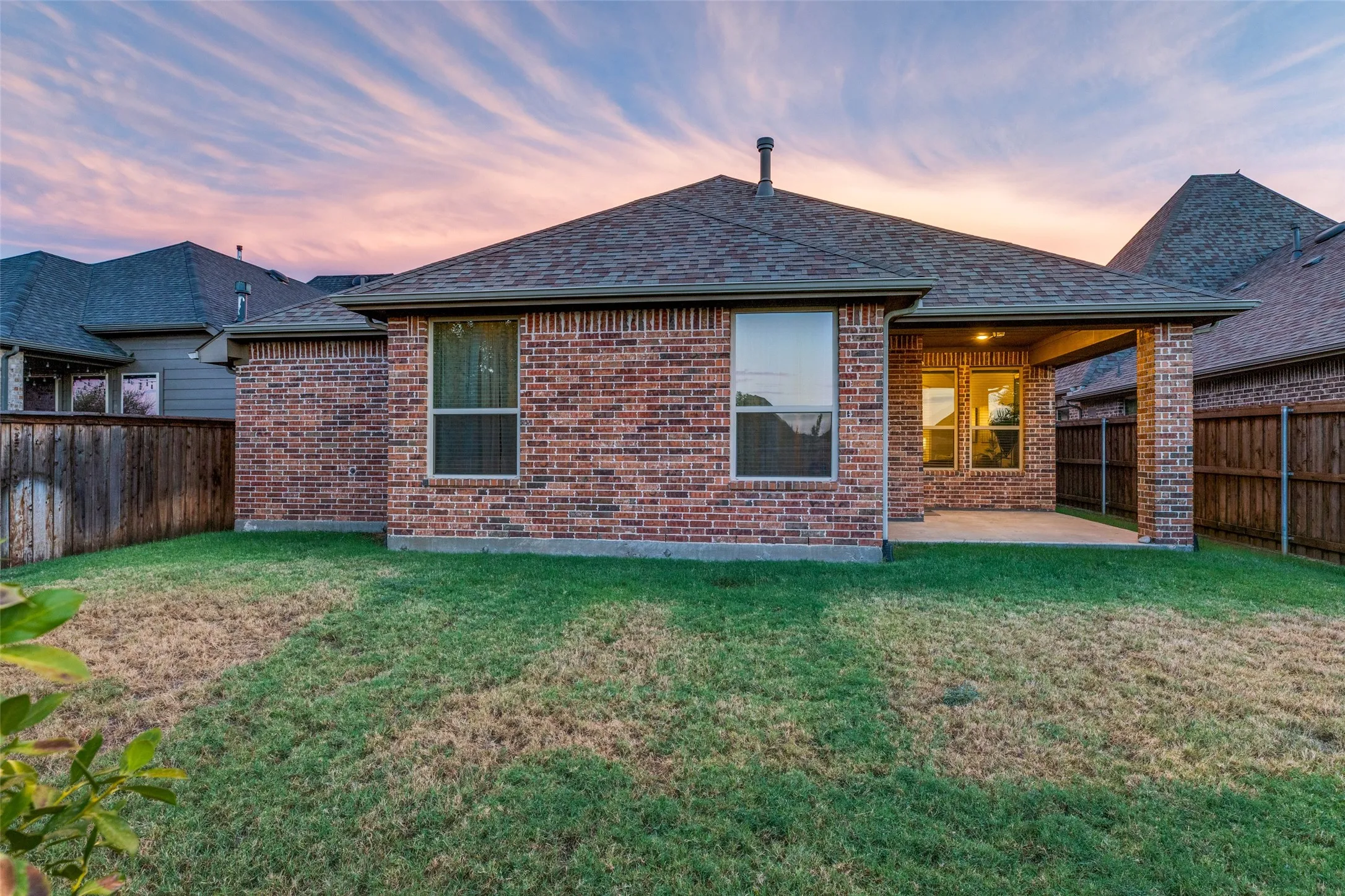 Brick exterior featuring a covered patio, multiple windows, and a shingle roof