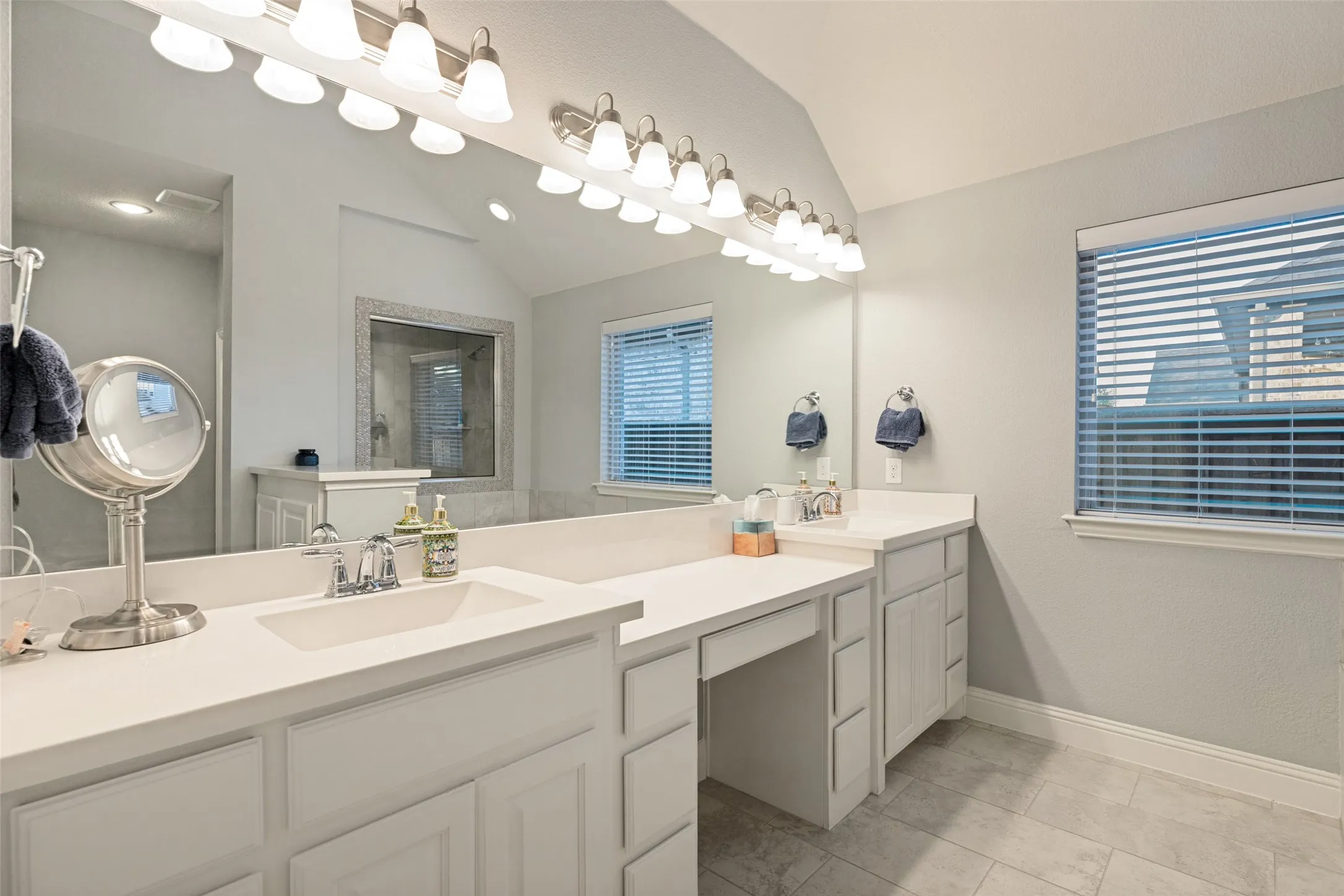 Dual vanity with integrated sinks, expansive counter space, built-in cabinetry, and tile flooring
