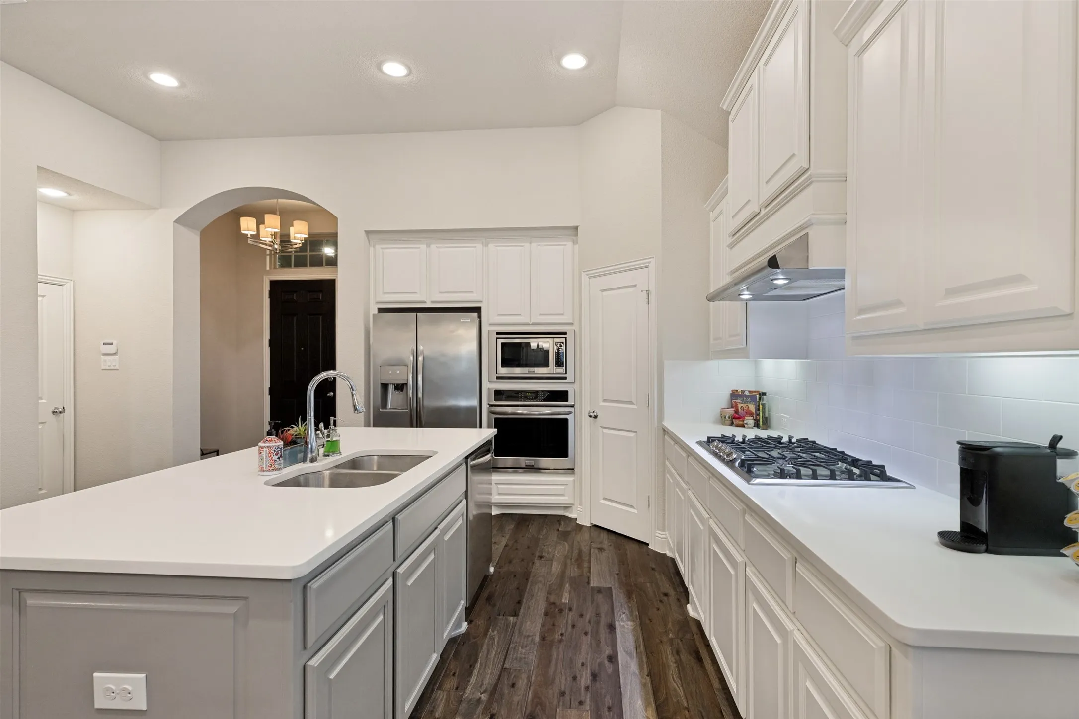 Kitchen featuring an island with a double basin sink, stainless steel appliances, recessed lighting, and wood-finish flooring