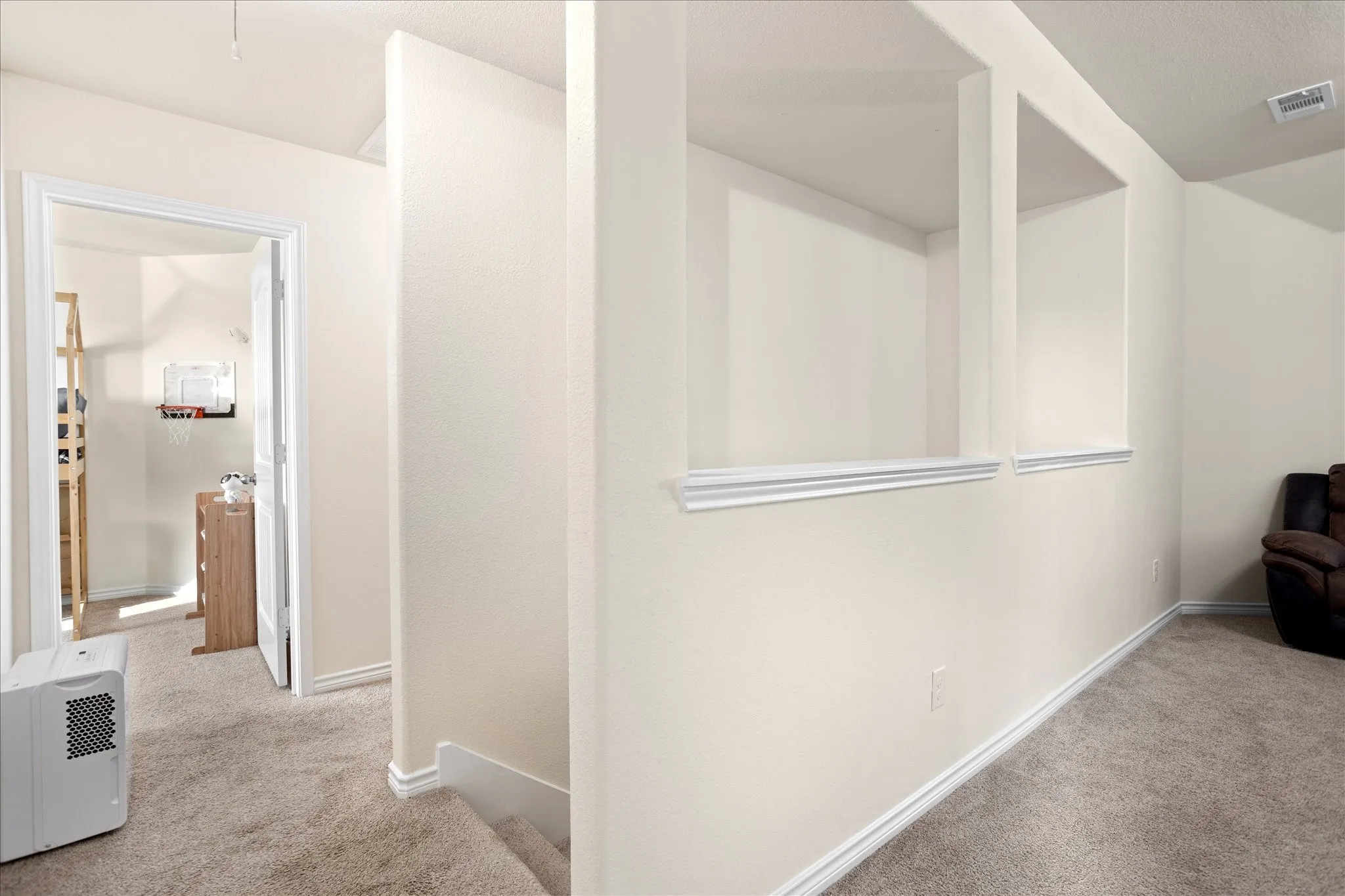 Carpeted hallway with architectural wall cutouts and white trim