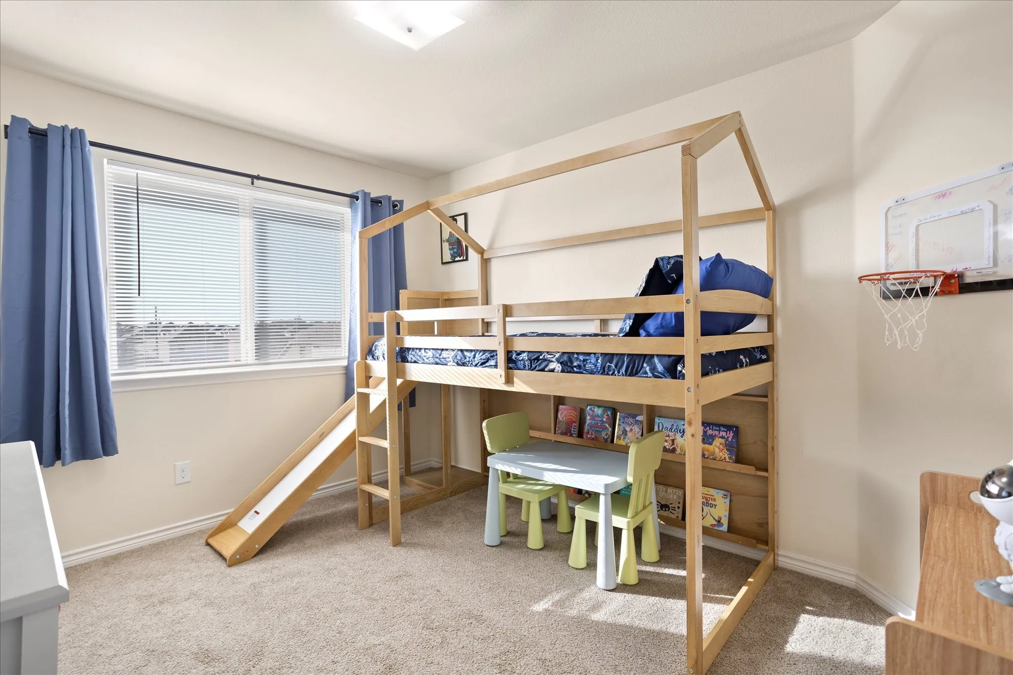 Carpeted room featuring a large window with blinds, blue curtains, and a flush-mount ceiling light