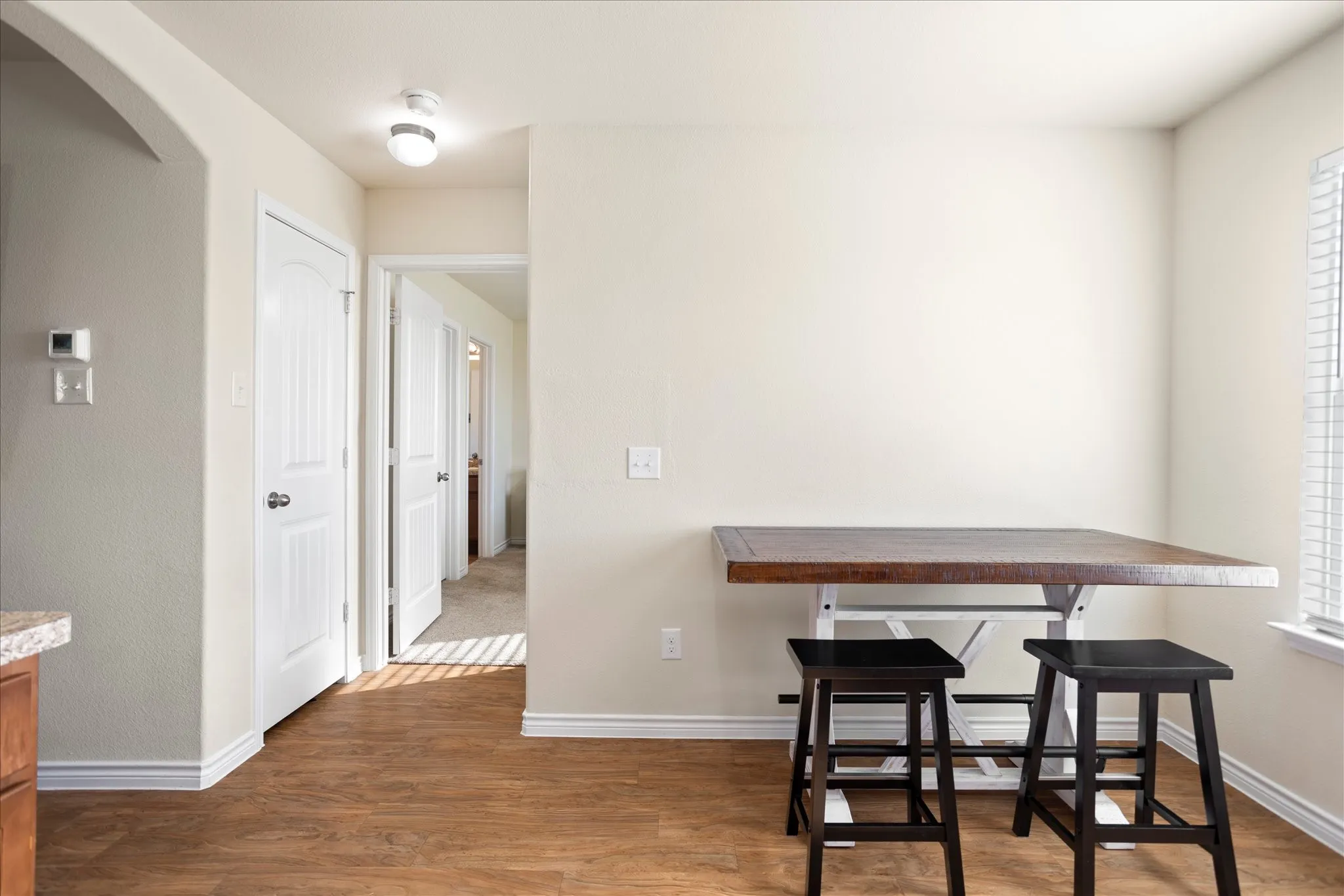 Wood-finish flooring throughout, complemented by a light-toned archway and crisp white trim
