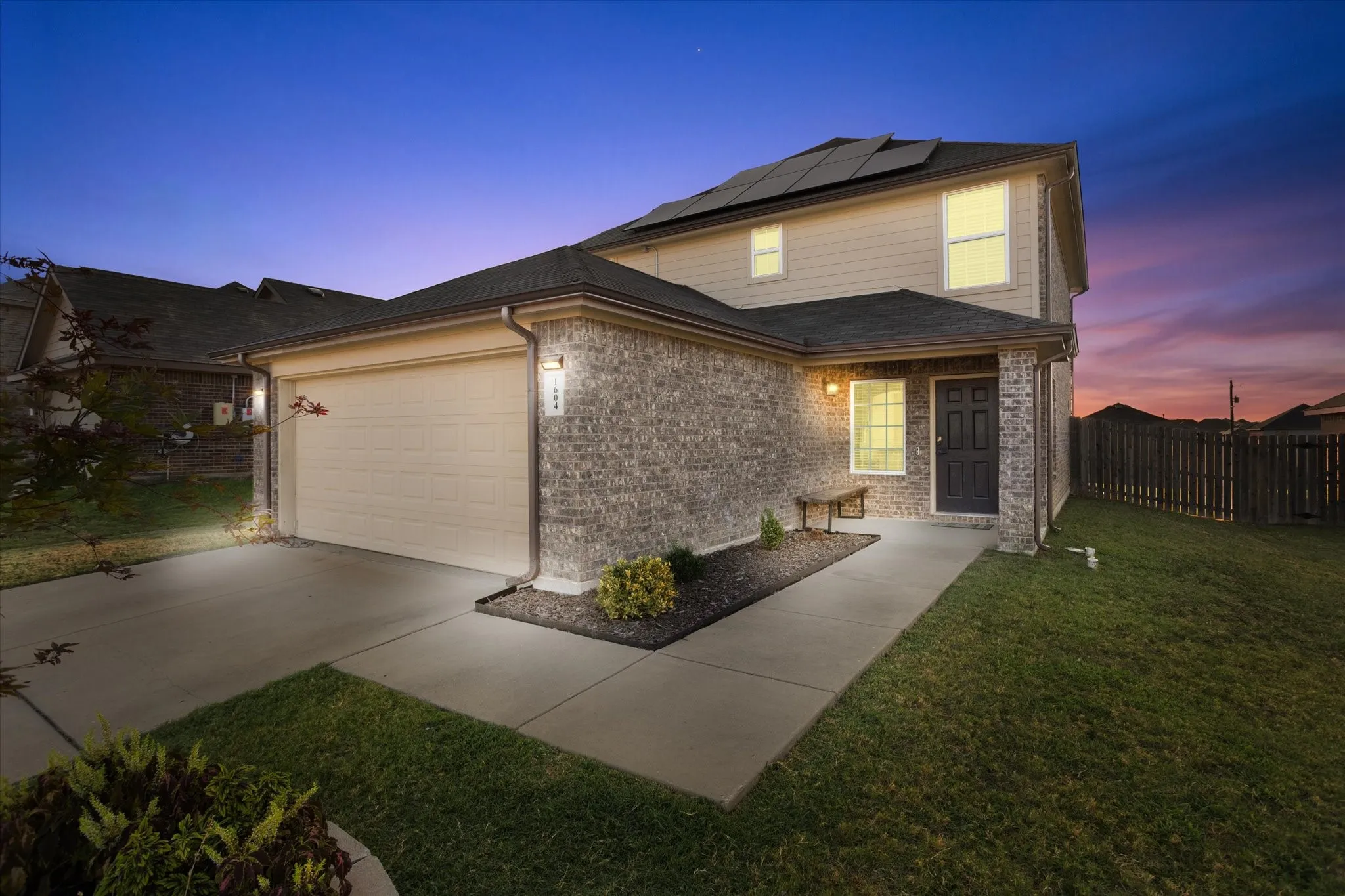 Brick and siding exterior with dark shingles, concrete driveway, and front walkway