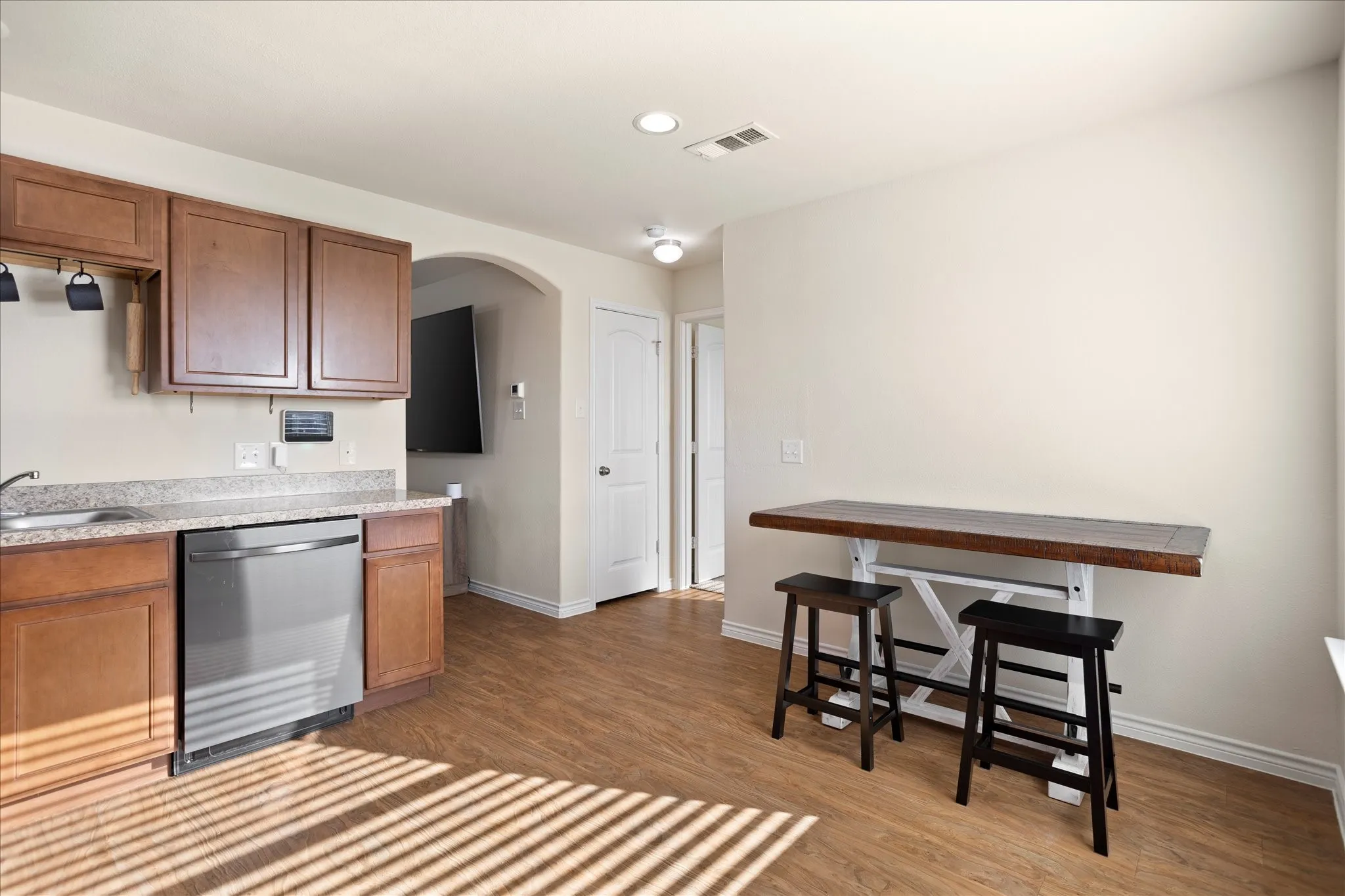 Wood-finish flooring throughout, with recessed lighting, an arched doorway, and a white interior door