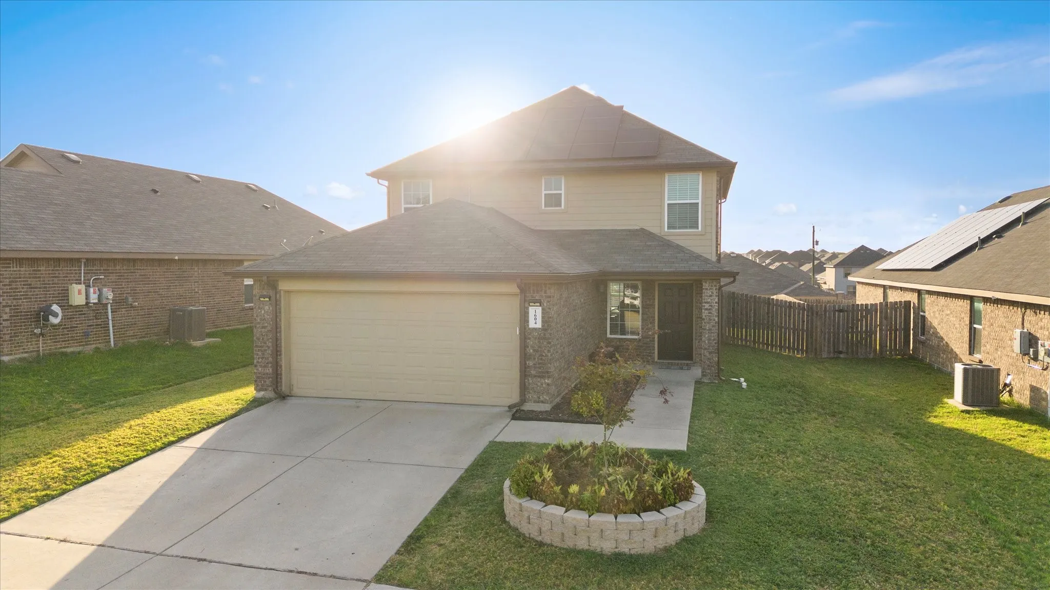 Two-story residence featuring a brick and siding exterior, an attached garage, a concrete driveway, a front entry, and a landscaped garden bed