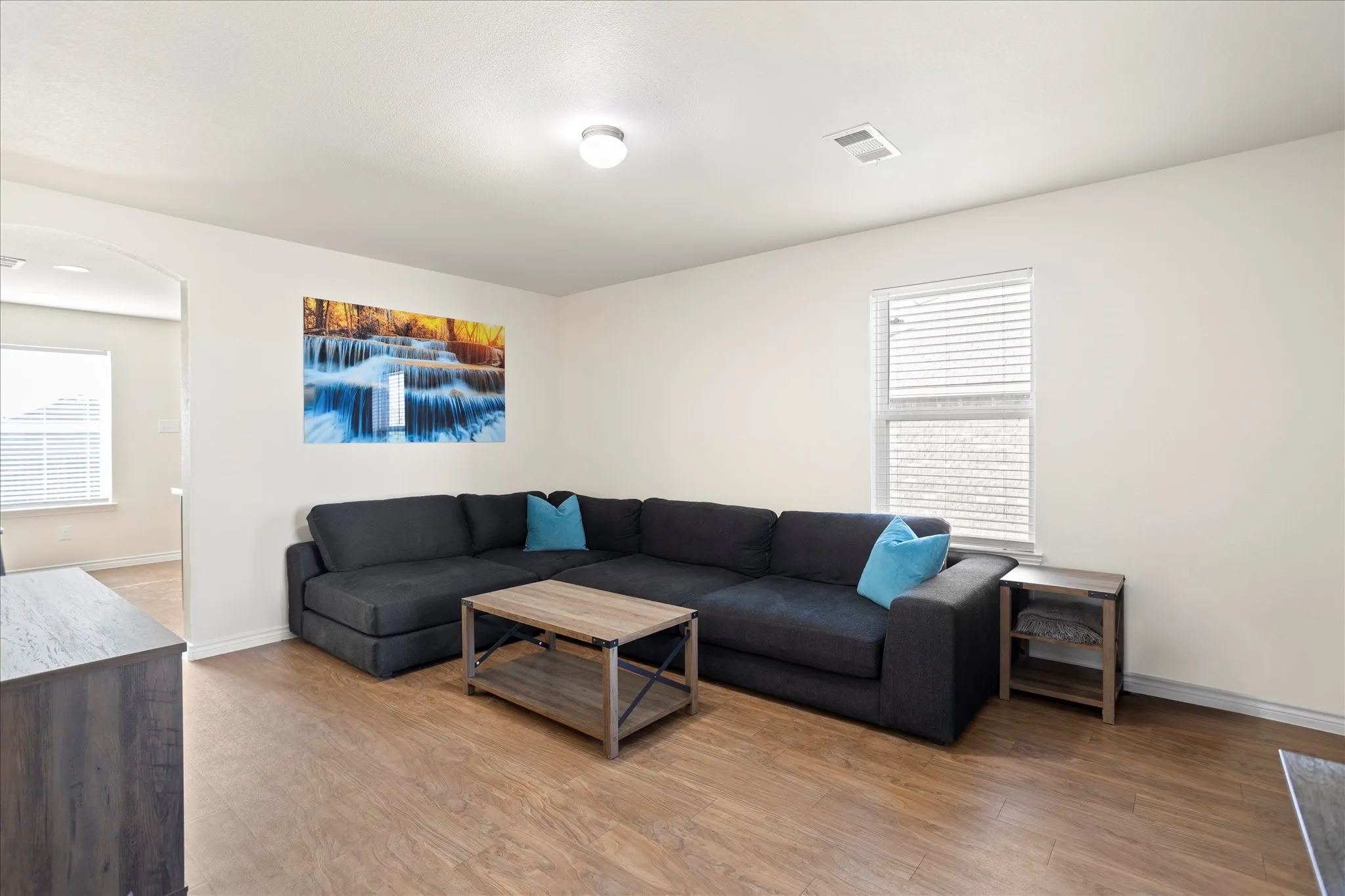 Wood-finish flooring throughout, complemented by light-toned walls and an arched doorway