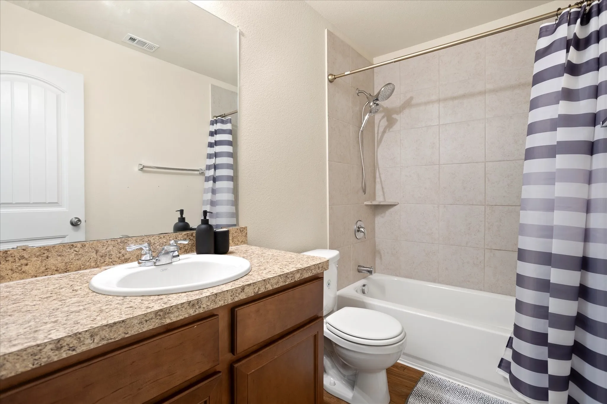 Vanity with an oval undermount sink, dual-handle faucet, and mottled countertop