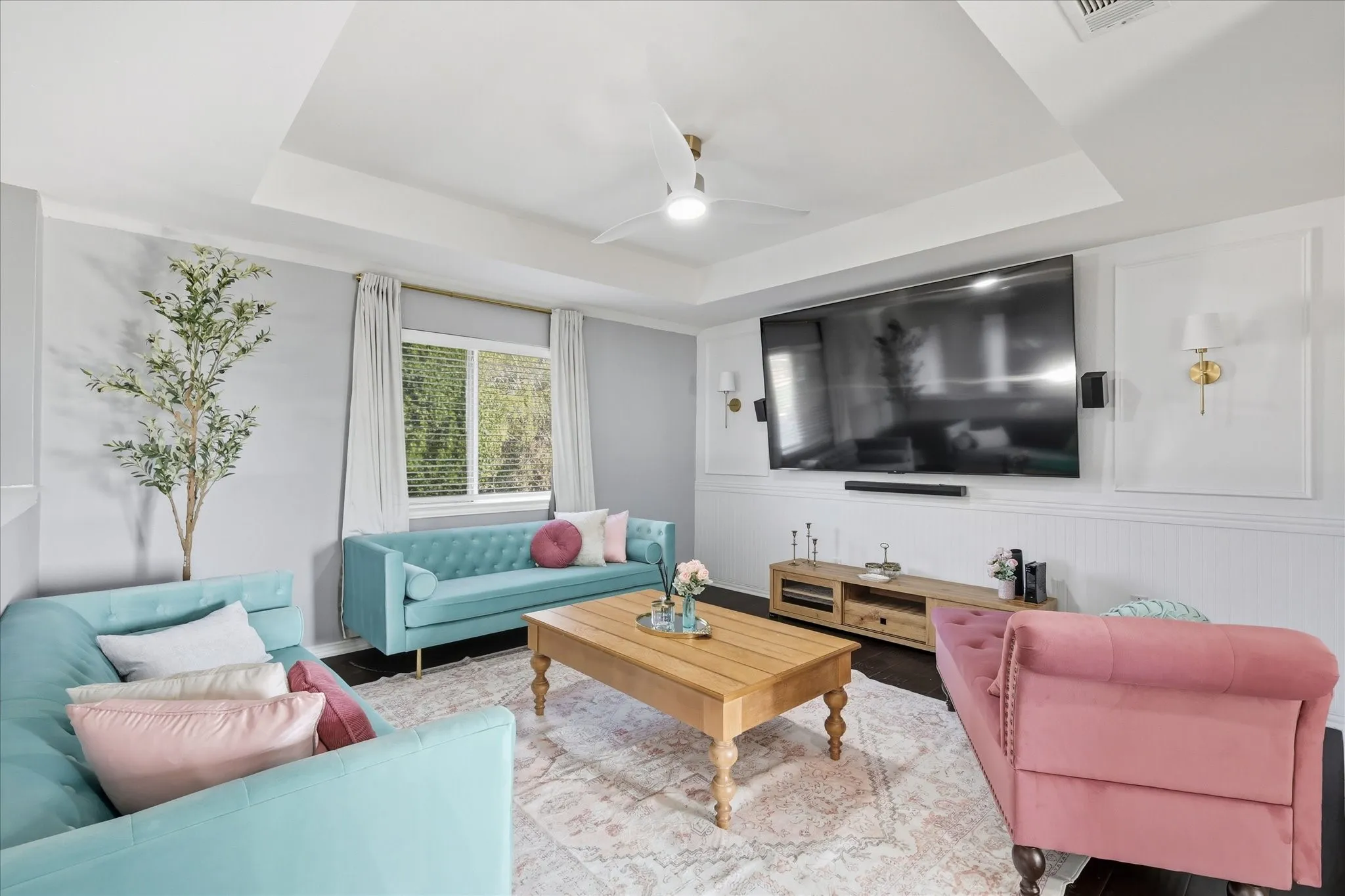 Tray ceiling with a ceiling fan, recessed lighting, wood-finish flooring, white beadboard wainscoting, and decorative wall molding with sconces
