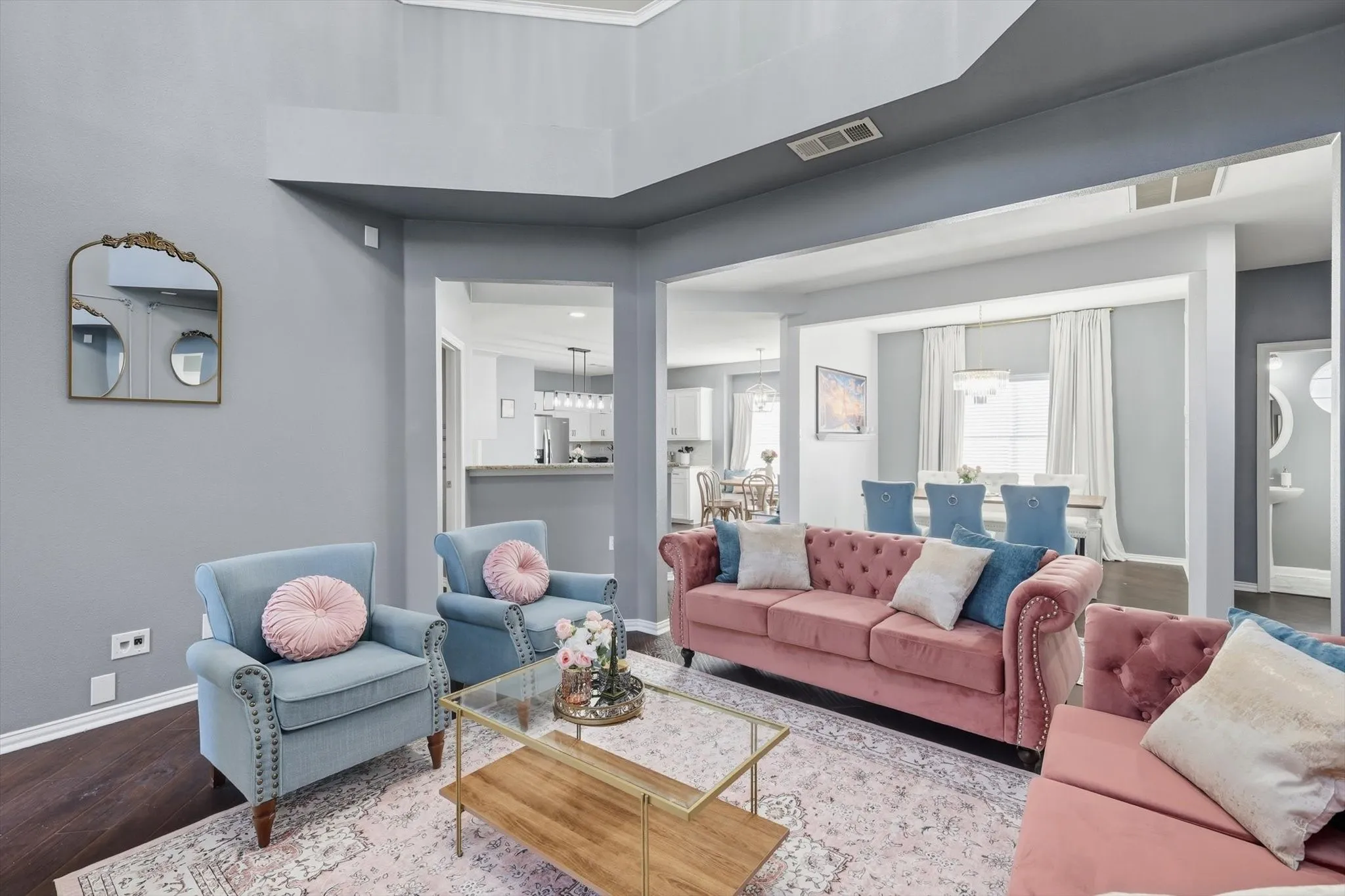 Spacious living area with high ceilings, dark wood-finish flooring, and light wall finishes