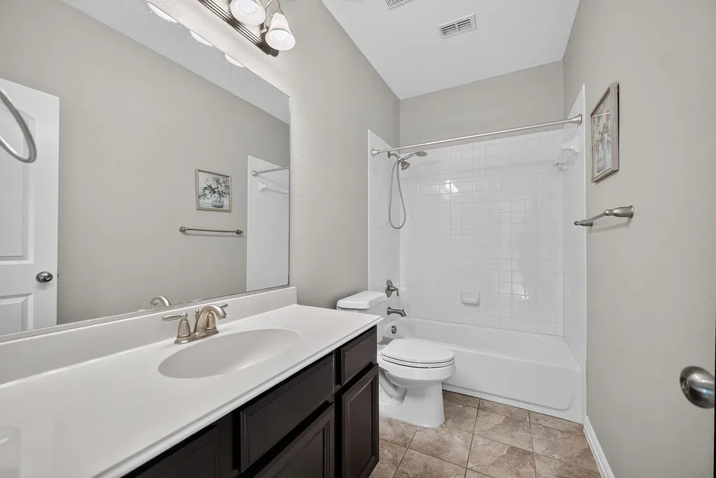 Dark wood-finish vanity with an integrated sink, brushed nickel faucet, and a large wall-mounted mirror