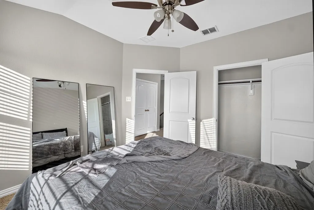 Vaulted ceiling with a ceiling fan, light gray wall paint, open closet with hanging rod, and two paneled interior doors