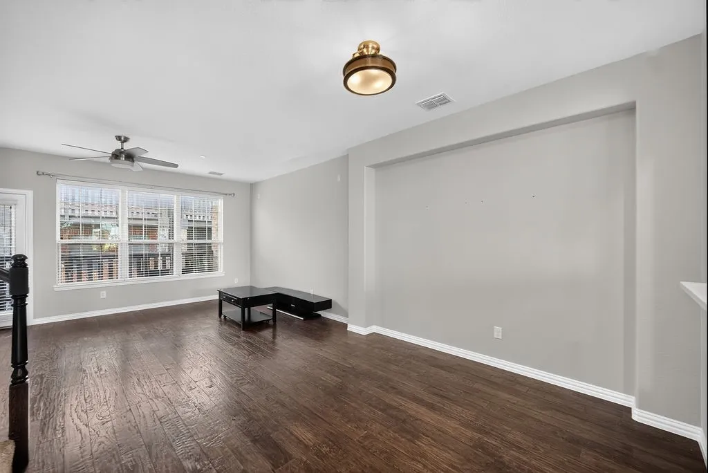 Hardwood-finish flooring, recessed wall niche, ceiling fan, and prominent window with blinds