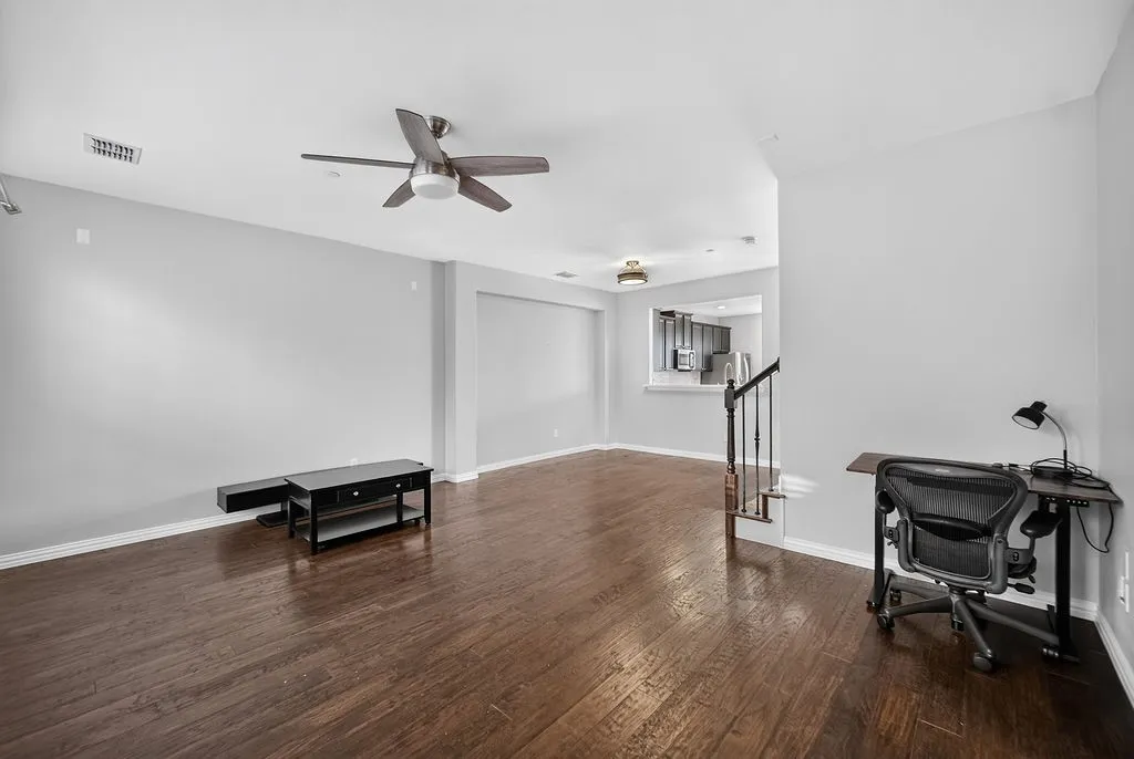 Hardwood-finish flooring, ceiling fan, and staircase with dark balusters