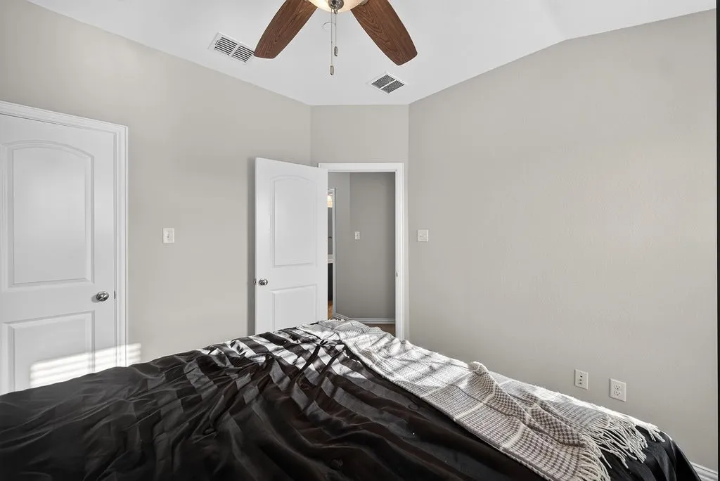 Vaulted ceiling with a wood-finish ceiling fan, neutral wall paint, and white paneled doors