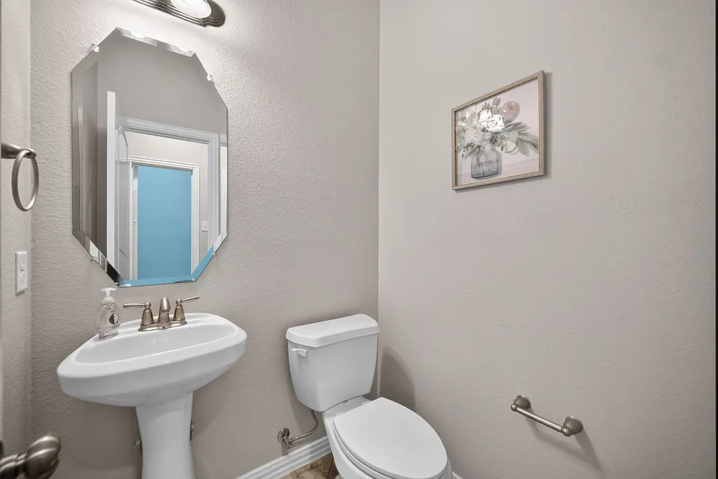 Pedestal sink with brushed nickel faucet, beveled wall mirror, and neutral wall​​‌​​​​‌​​‌‌​‌‌​​​‌‌​‌​‌​‌​​​‌​​ paint