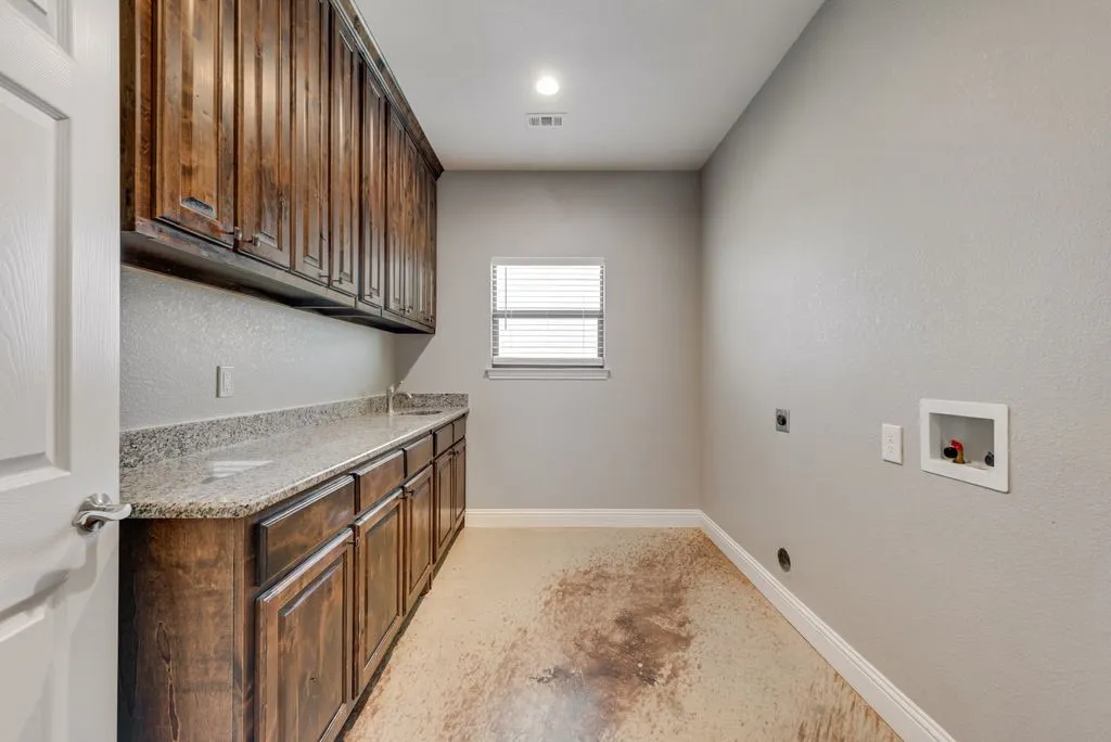 This oversize laundry space has a bank of upper and lower cabinets, as well as a long granite topped counter. Great spot for party set up or assistance folding laundry.