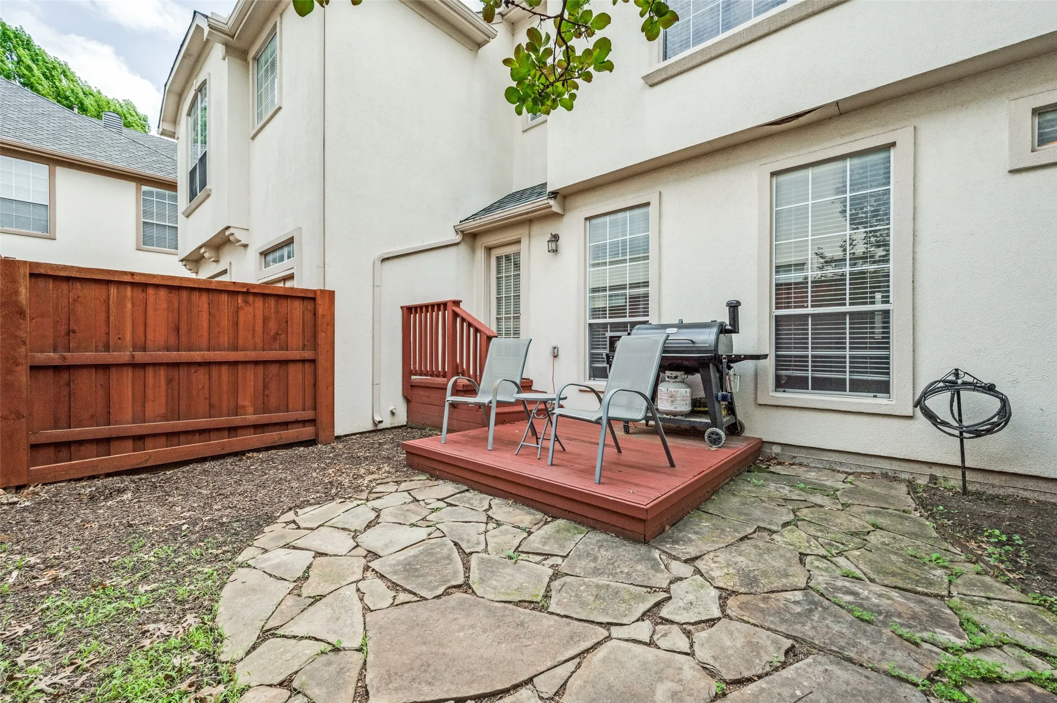 Private outdoor patio featuring a flagstone walkway, wood deck, and wood privacy fence