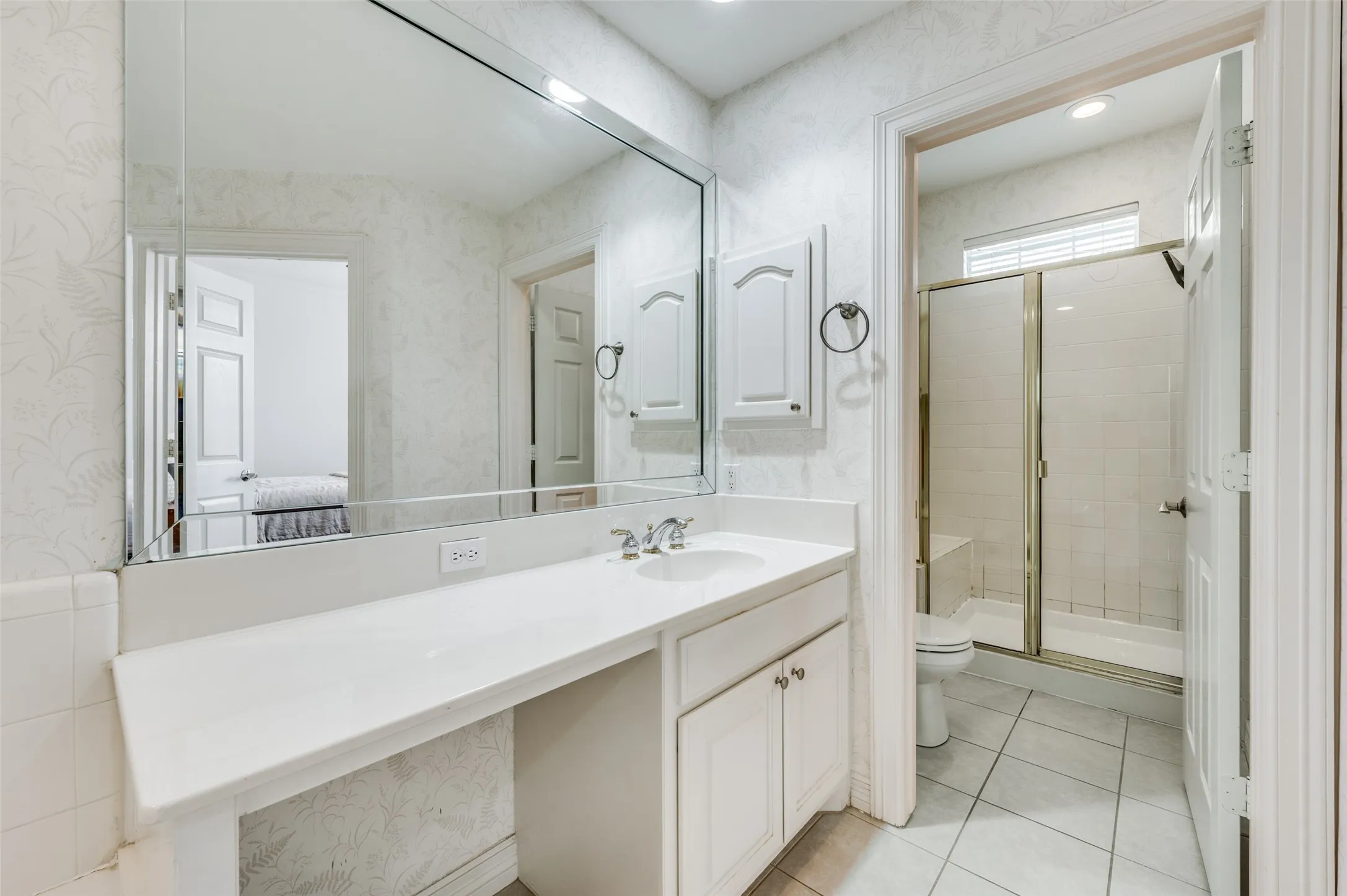 White vanity with integrated sink, chrome faucet, and expansive mirror