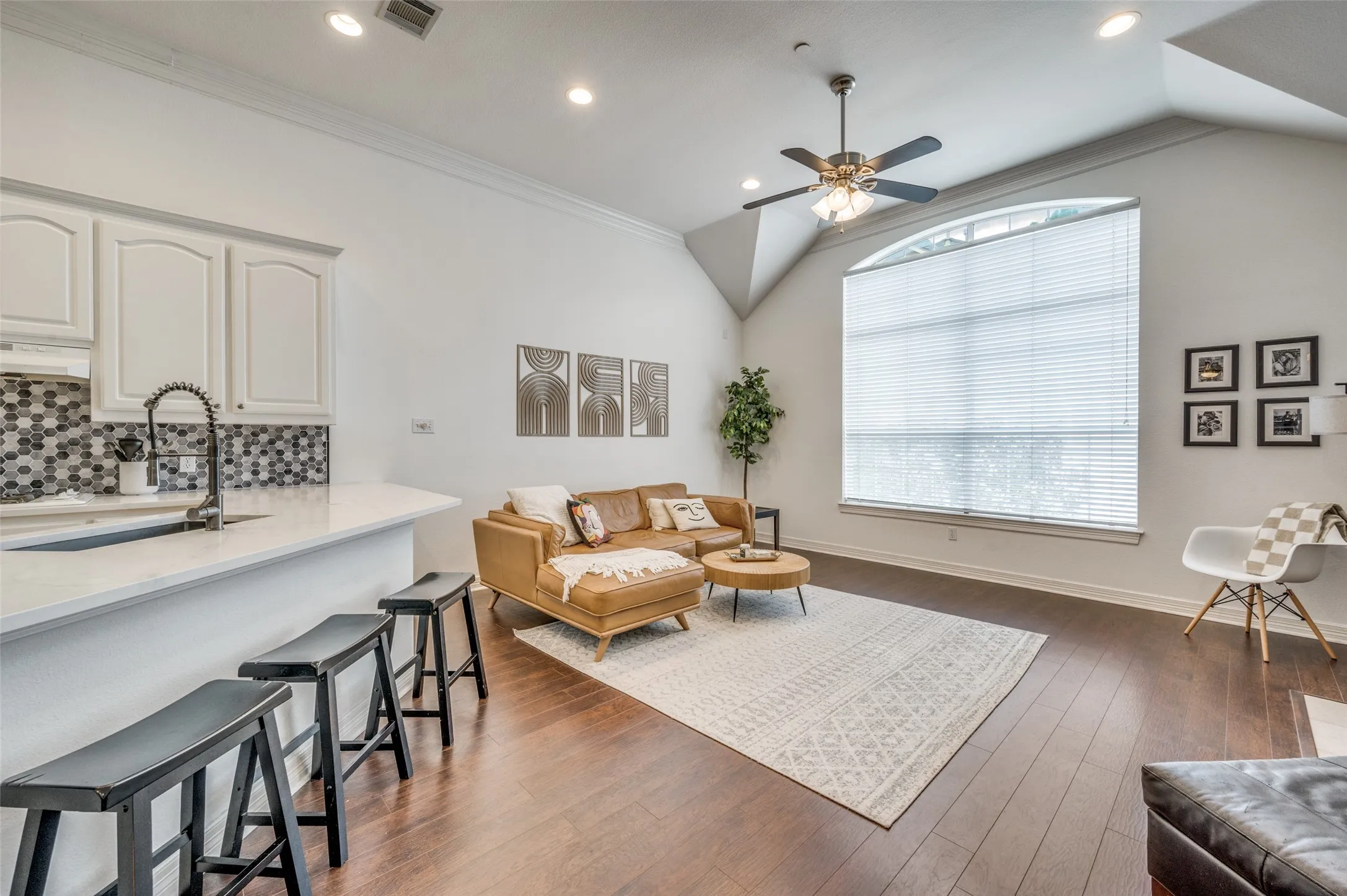 Vaulted ceiling, recessed lighting, wood-finish flooring, large arched window, and a built-in ceiling fan