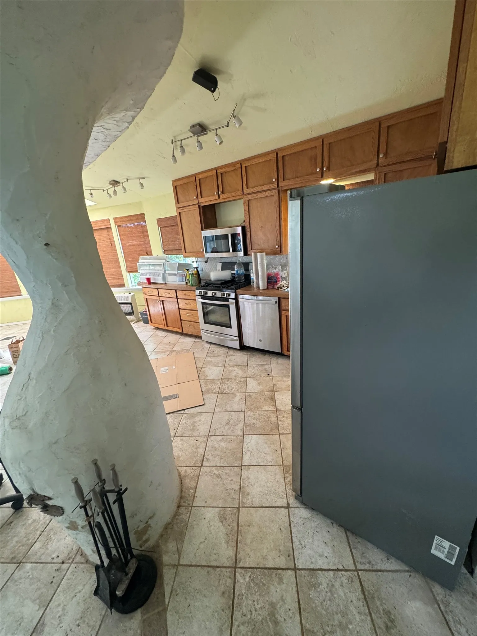 Kitchen featuring full-height wood cabinetry, stainless steel appliances, and track lighting