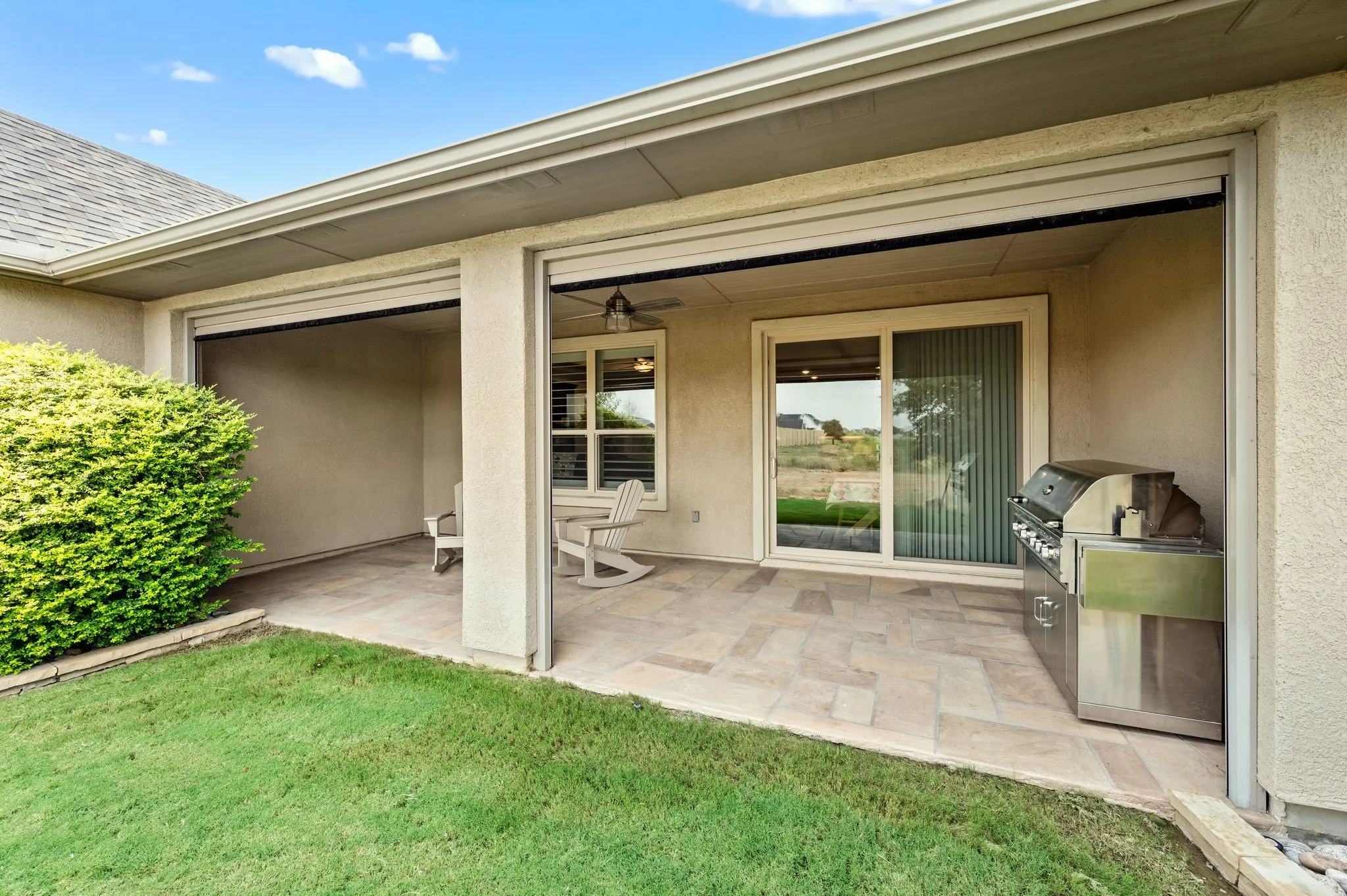 Covered patio with limestone coating, privacy wall, gas stub for grill and electric screen
