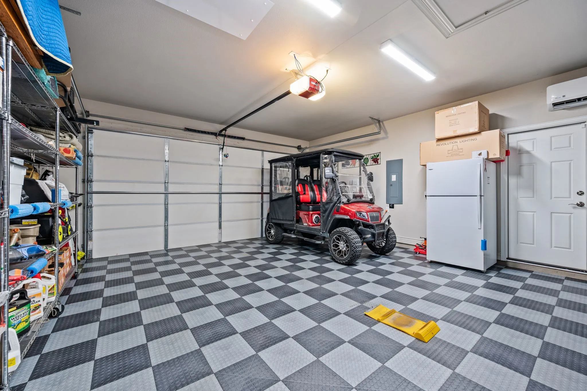 Garage with tile, AC, exterior door, utility sink, ice maker and attic lift