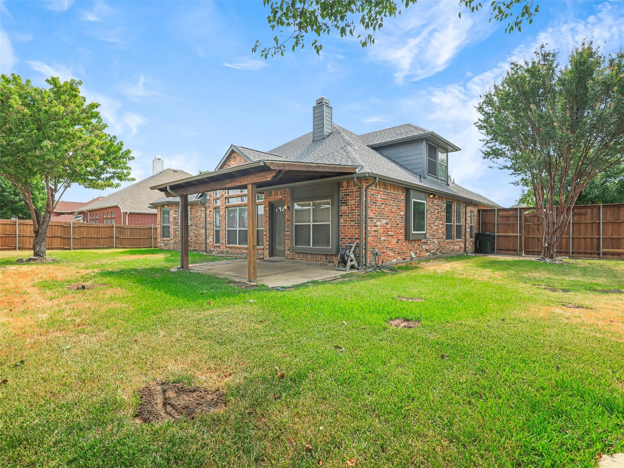 Brick exterior with a covered patio, wood beam accents, and a dormer window