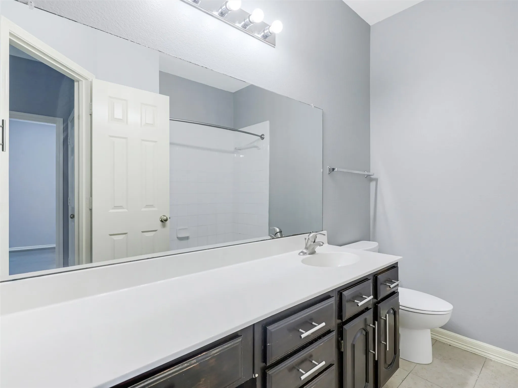 Vanity with integrated sink, dark wood-finish cabinetry, and brushed nickel hardware