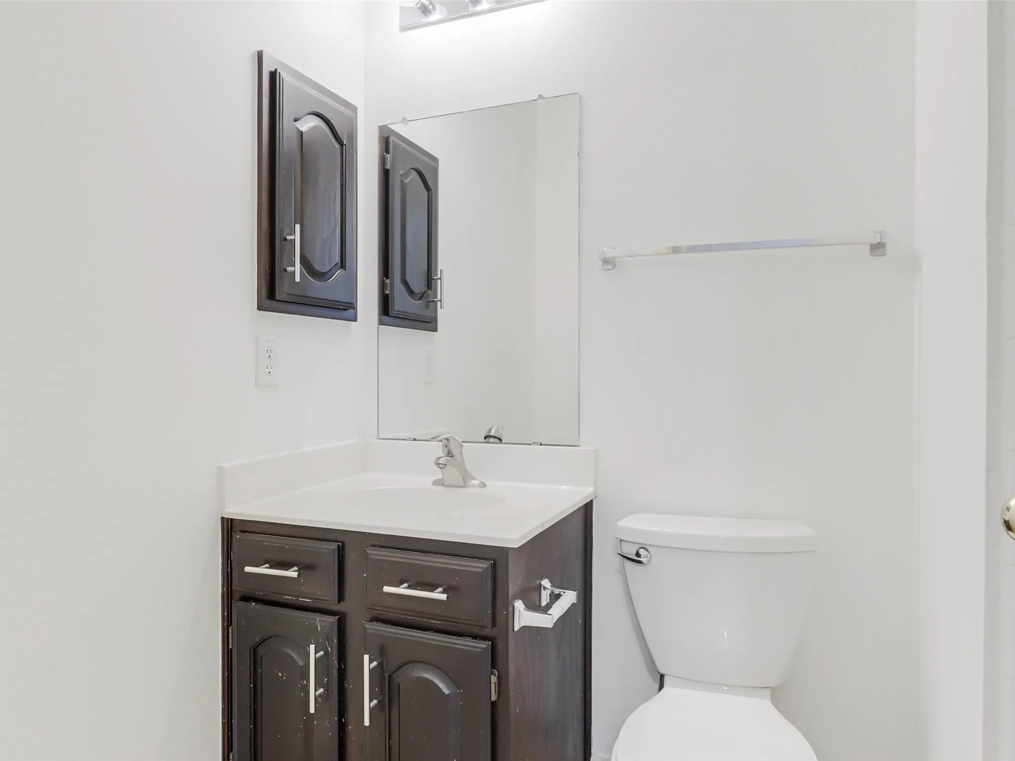Dark wood-finish vanity with a white countertop and integrated sink