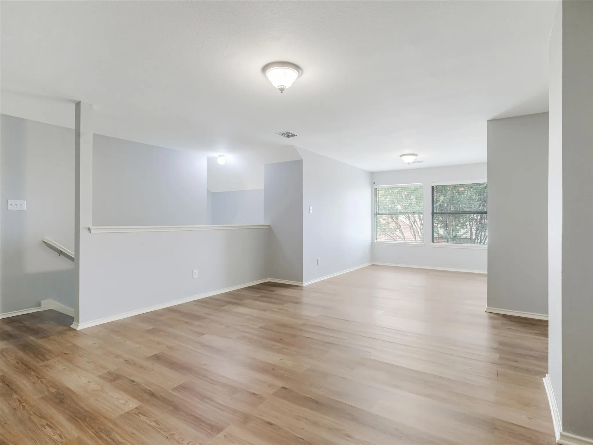 Wood-finish flooring throughout, light gray wall paint, and multiple windows