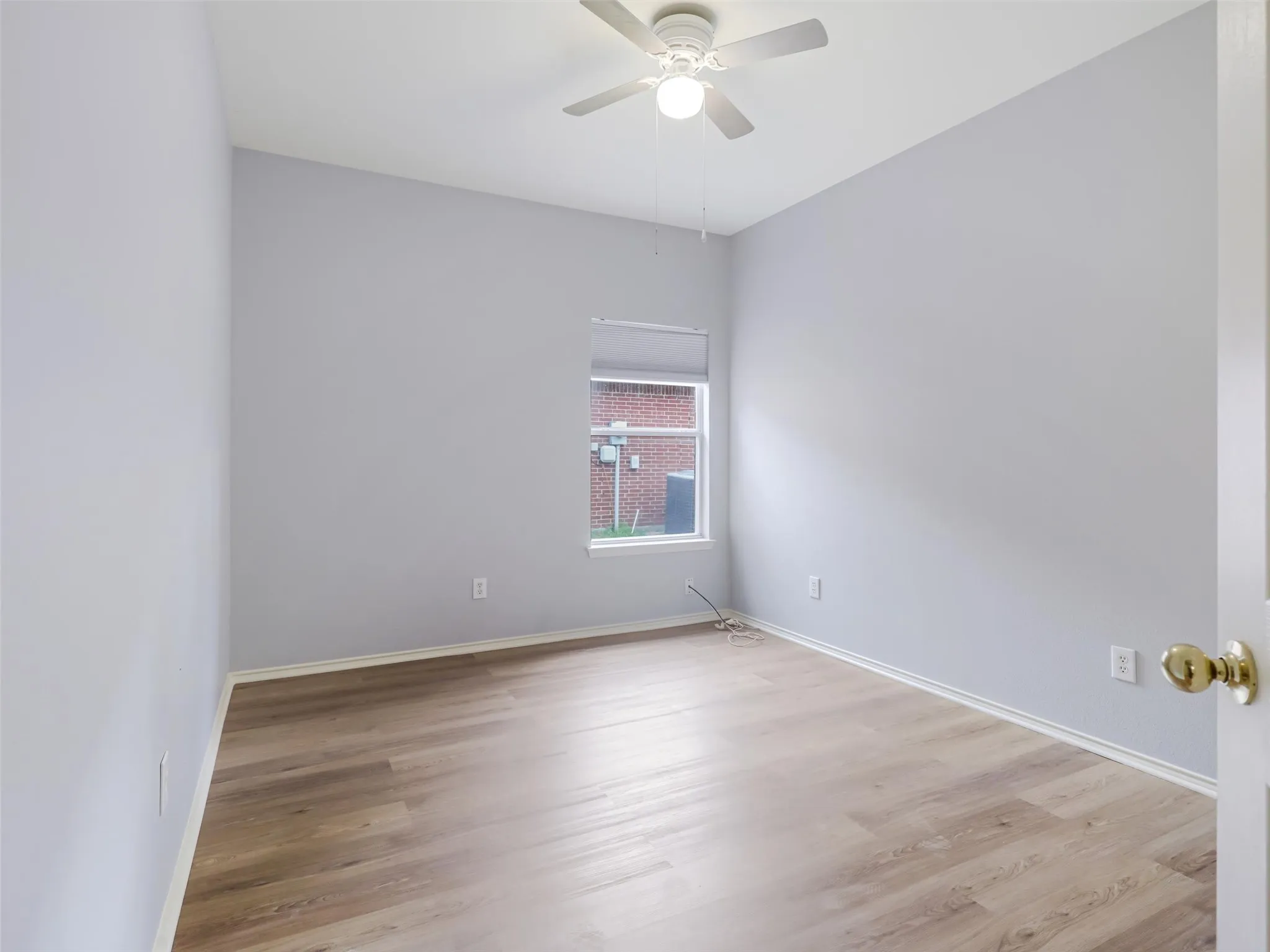 Wood-finish flooring, ceiling fan with integrated lighting, and window with roller shade