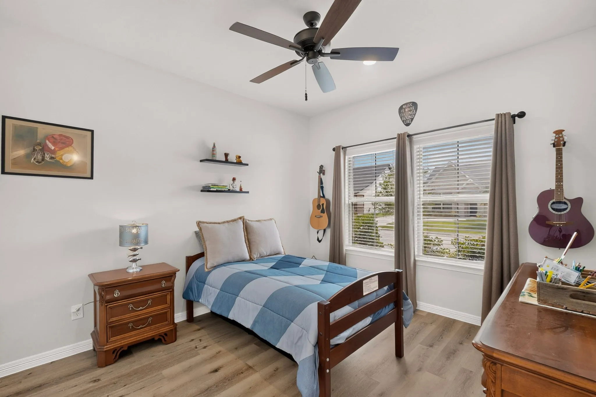 Wood-finish flooring, ceiling fan with integrated lighting, and two windows with blinds, walk in closet