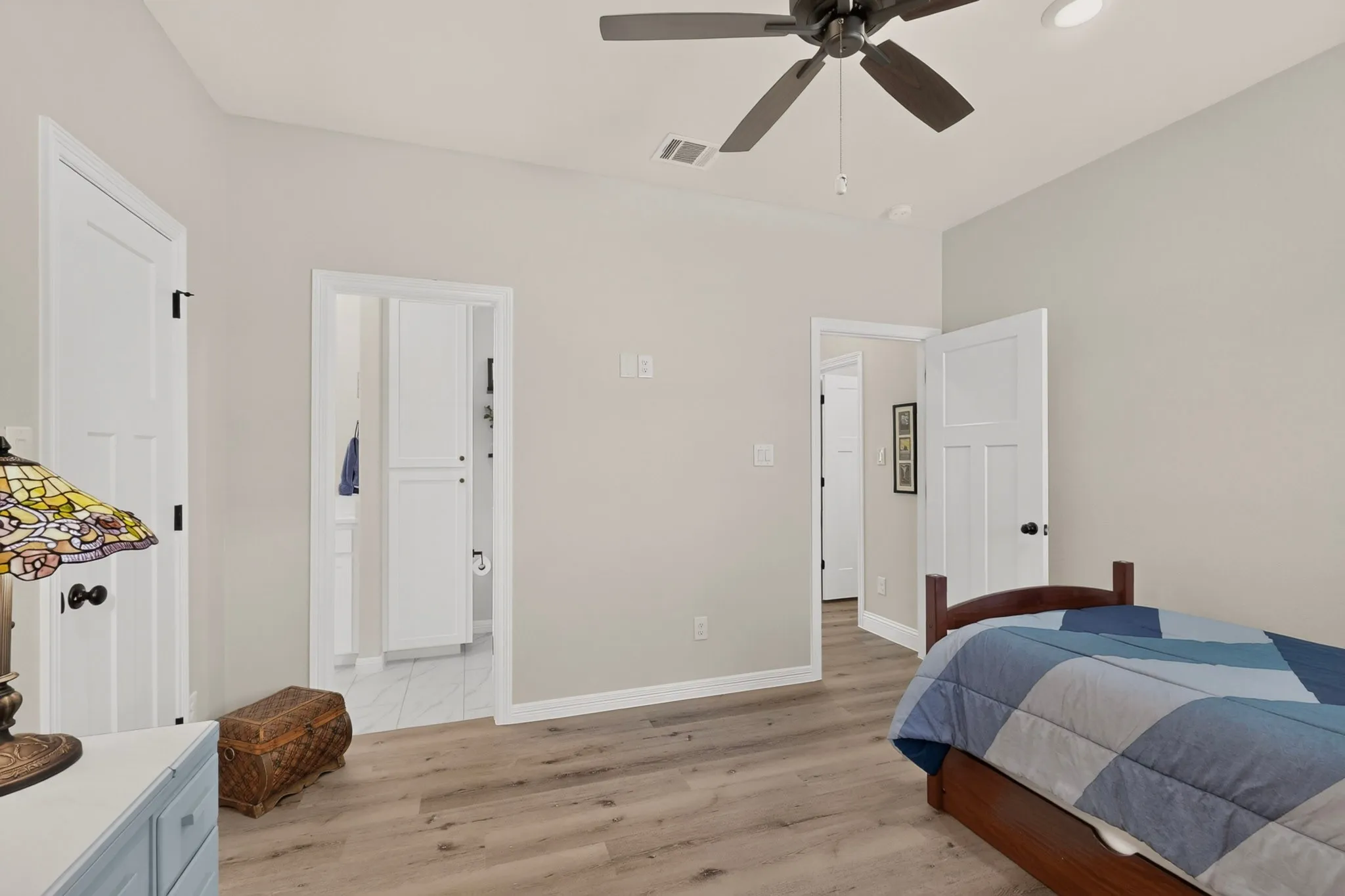 Wood-finish flooring, recessed lighting, ceiling fan, white interior doors, and a built-in cabinet