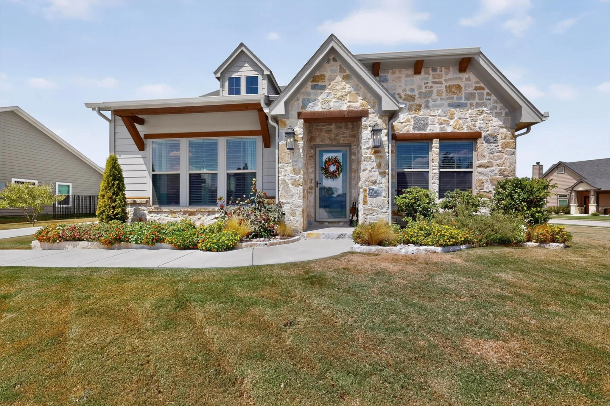 Stone and siding exterior with wood accents, large front windows, and established landscaping