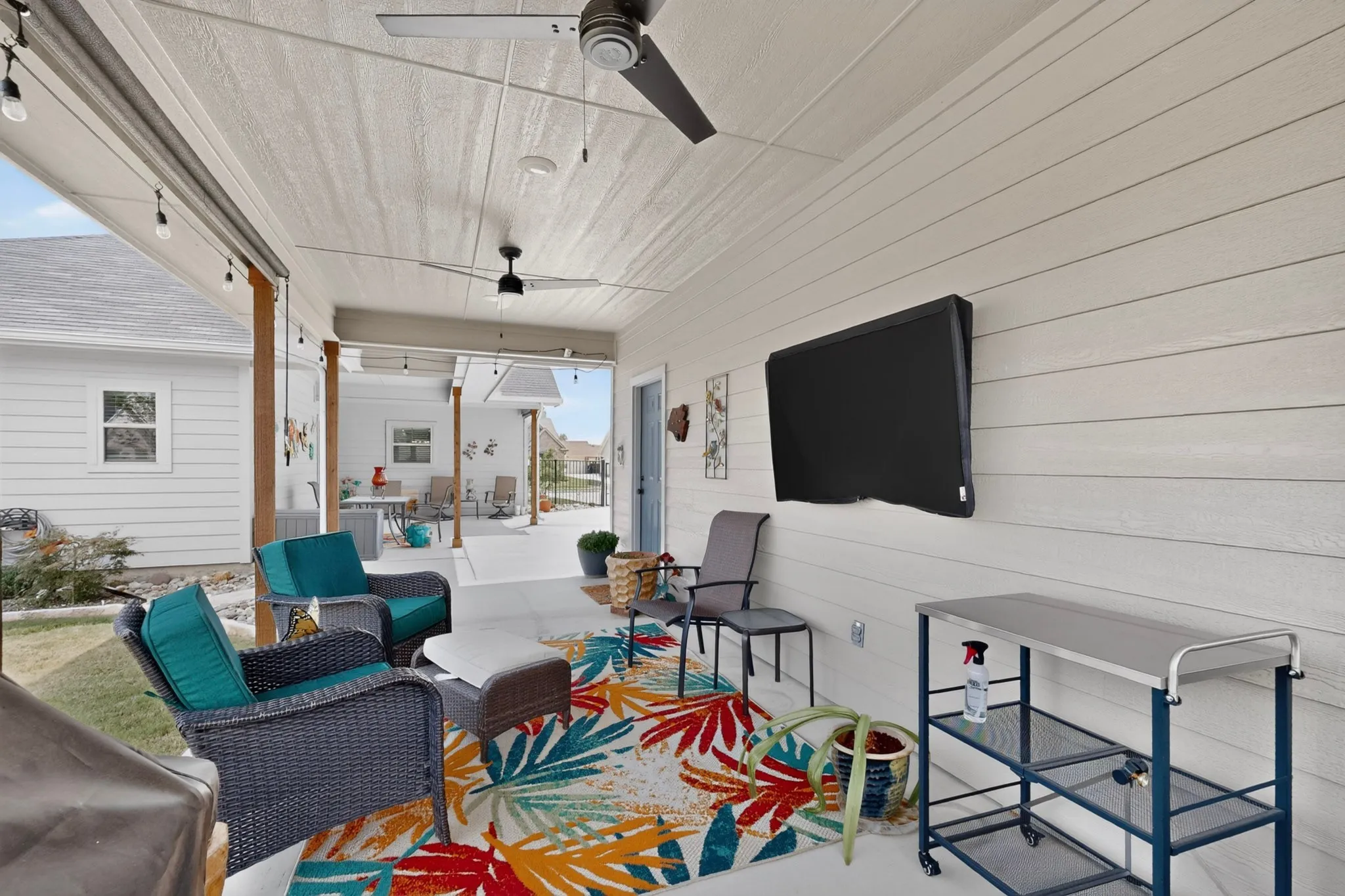 Covered patio featuring two outdoor ceiling fan, mounted TV and recessed lights, eve plugs and cedar wrapped post