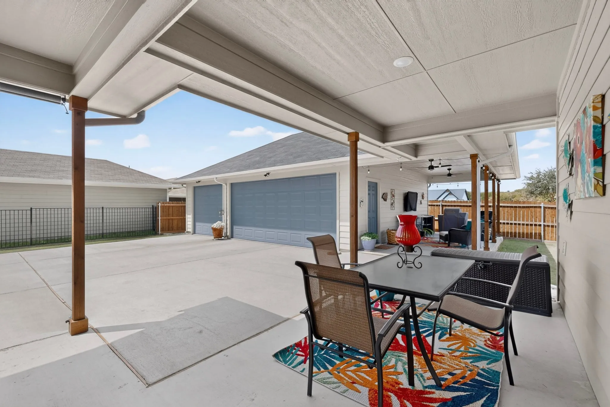 Covered patio with recessed lighting, wood-finish support columns, and an extended concrete pad
