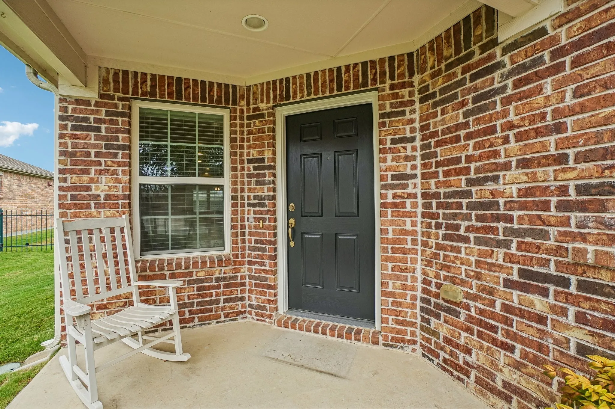 Brick exterior with a covered porch, recessed lighting, and a dark paneled entry door
