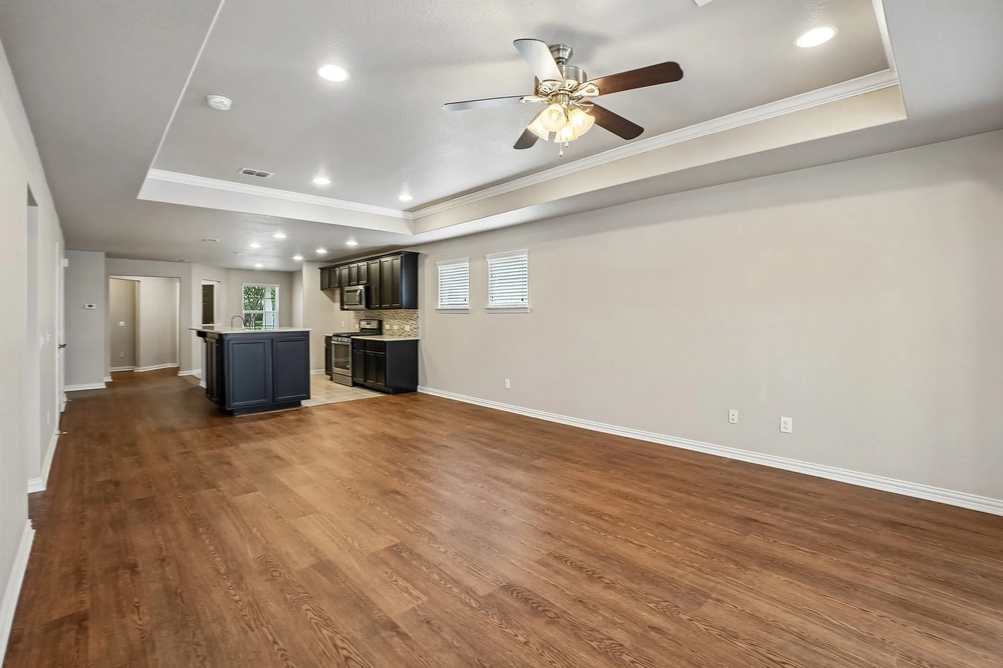 Expansive common area featuring wood-finish flooring, a recessed ceiling with crown molding, and recessed lighting