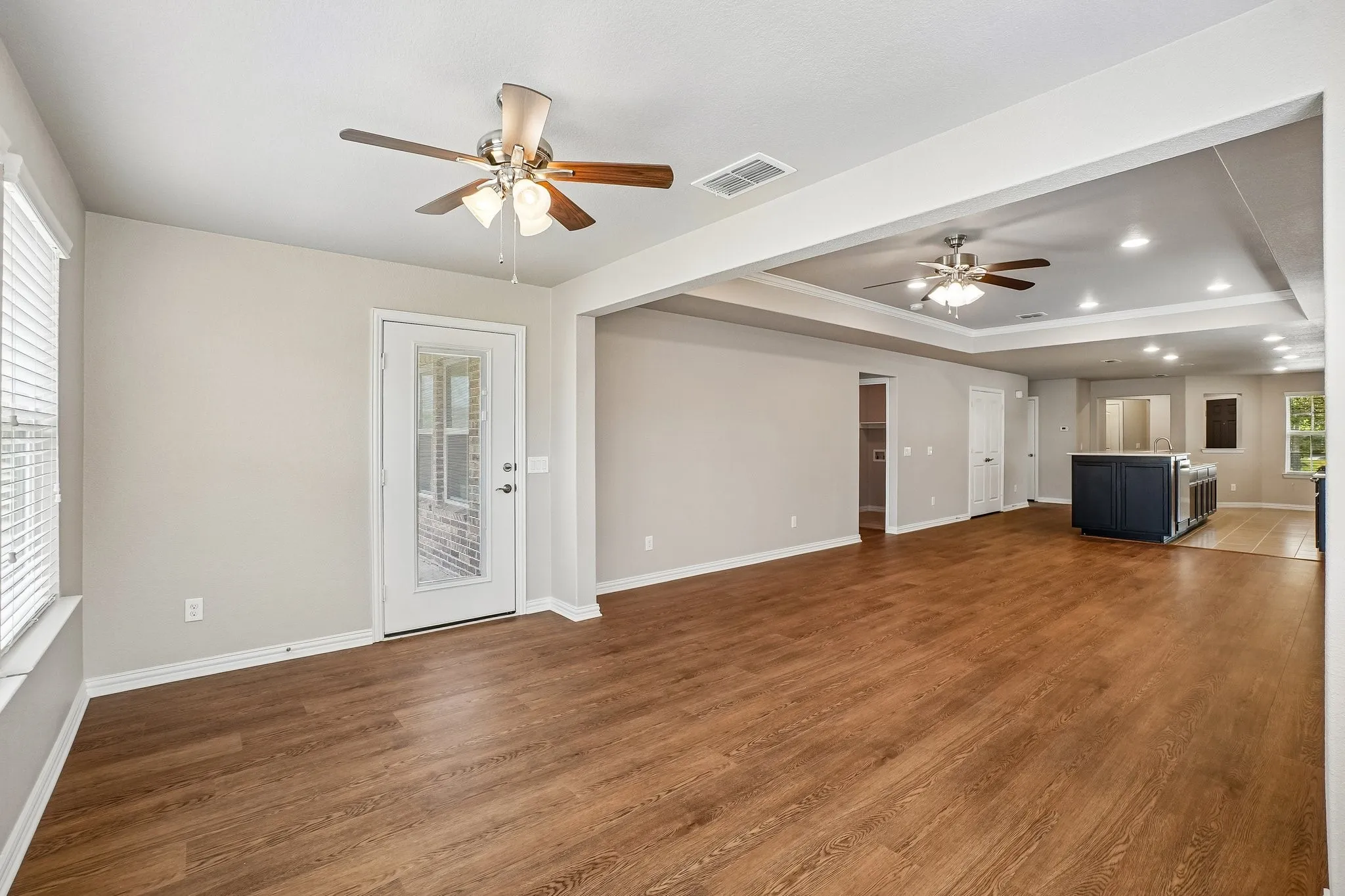 Open-concept living area featuring wood-finish flooring, recessed lighting, and a white paneled door with integrated window