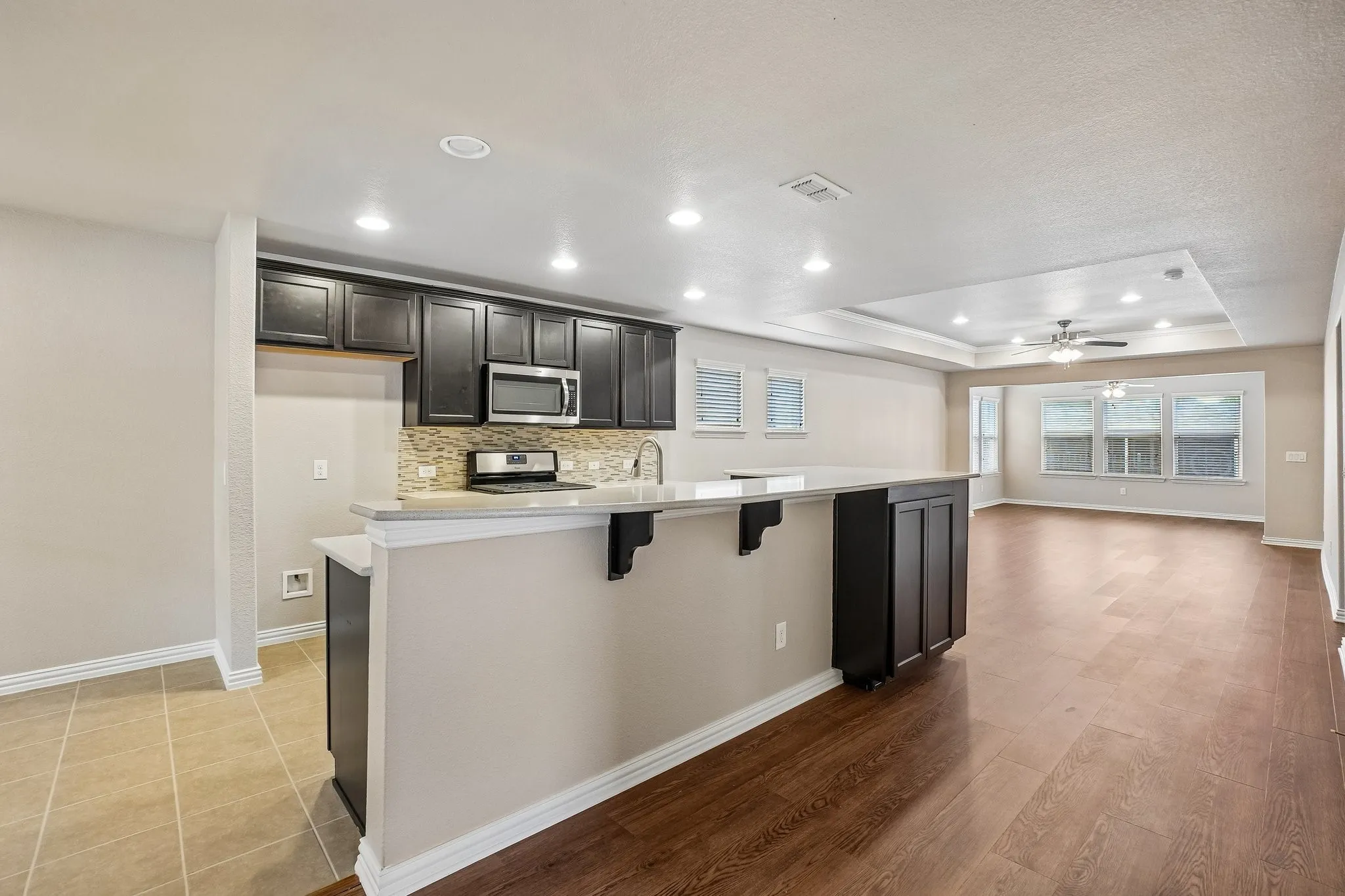 Kitchen featuring dark wood cabinetry, stainless steel appliances, a tile backsplash, and a breakfast bar