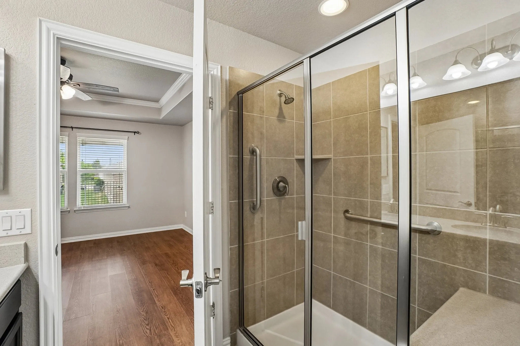 Glass-enclosed shower with tile surround, built-in bench, and grab bars