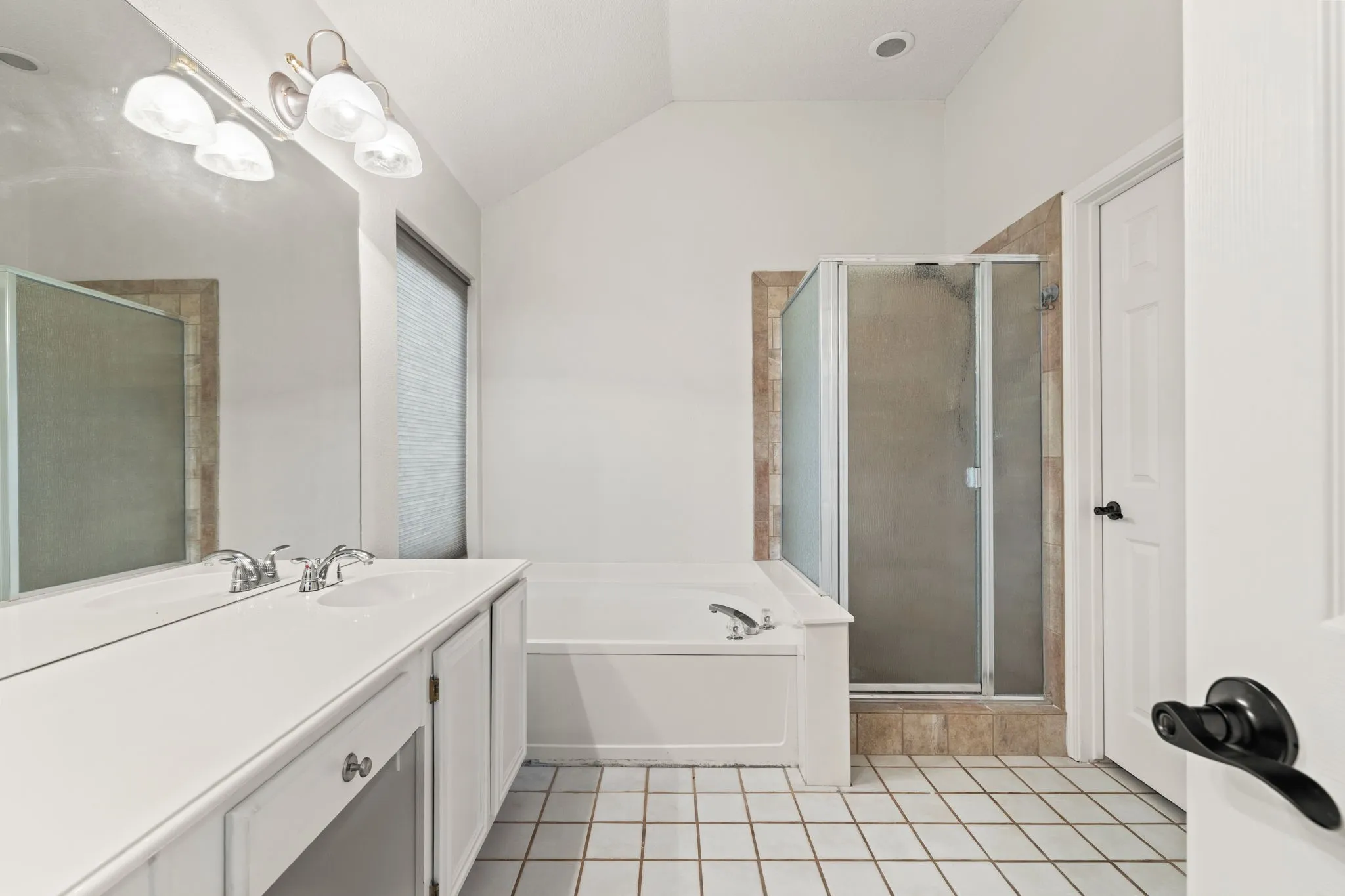 Dual vanity with polished chrome faucets, tile flooring, glass-enclosed shower, and built-in tub