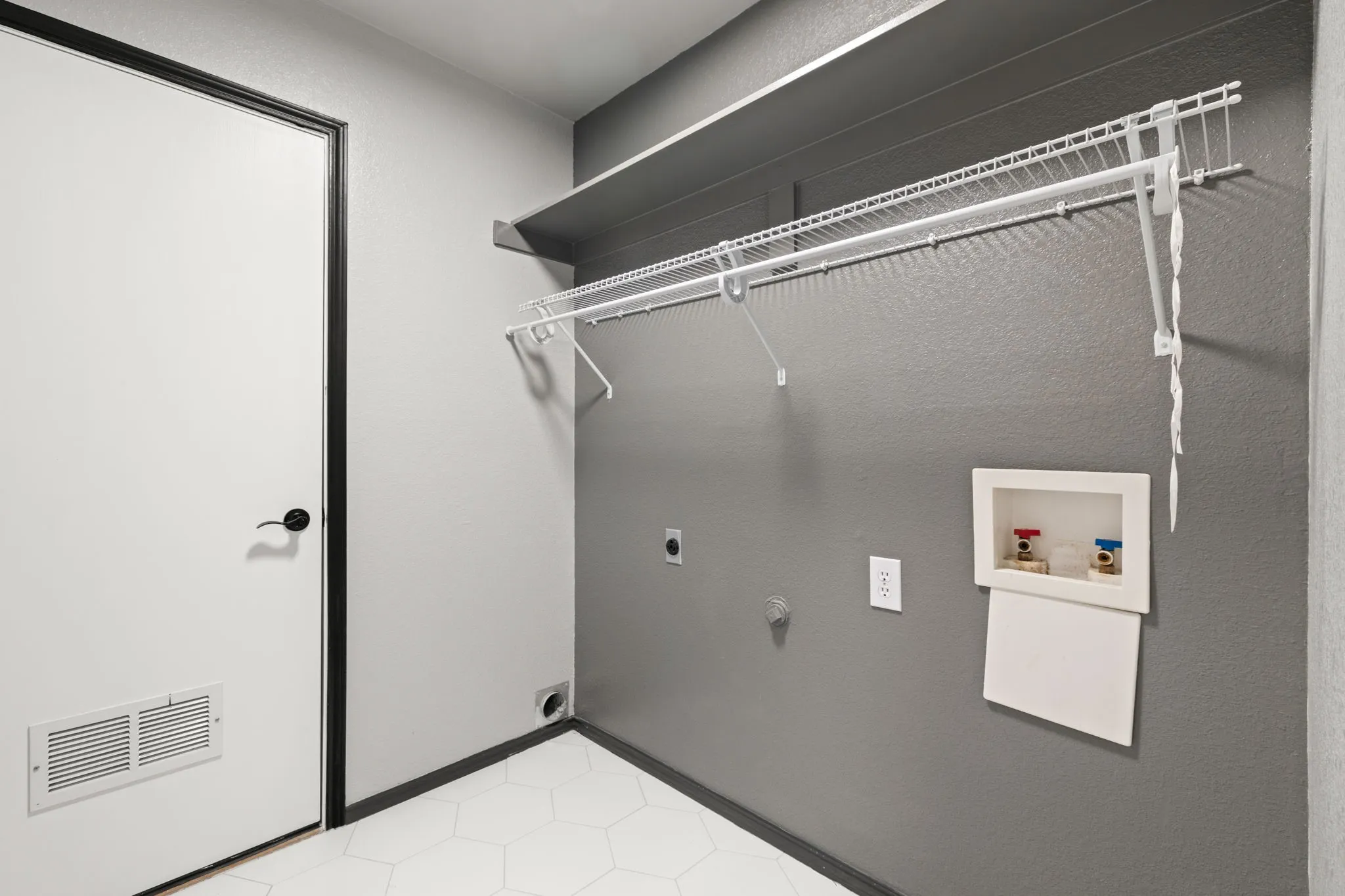 Built-in wire shelving, wall-mounted utility hookups, and a contemporary black door