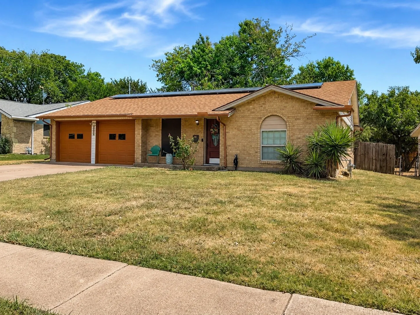 Brick exterior with a brown shingle roof, two garage doors with window inserts, and a front entry