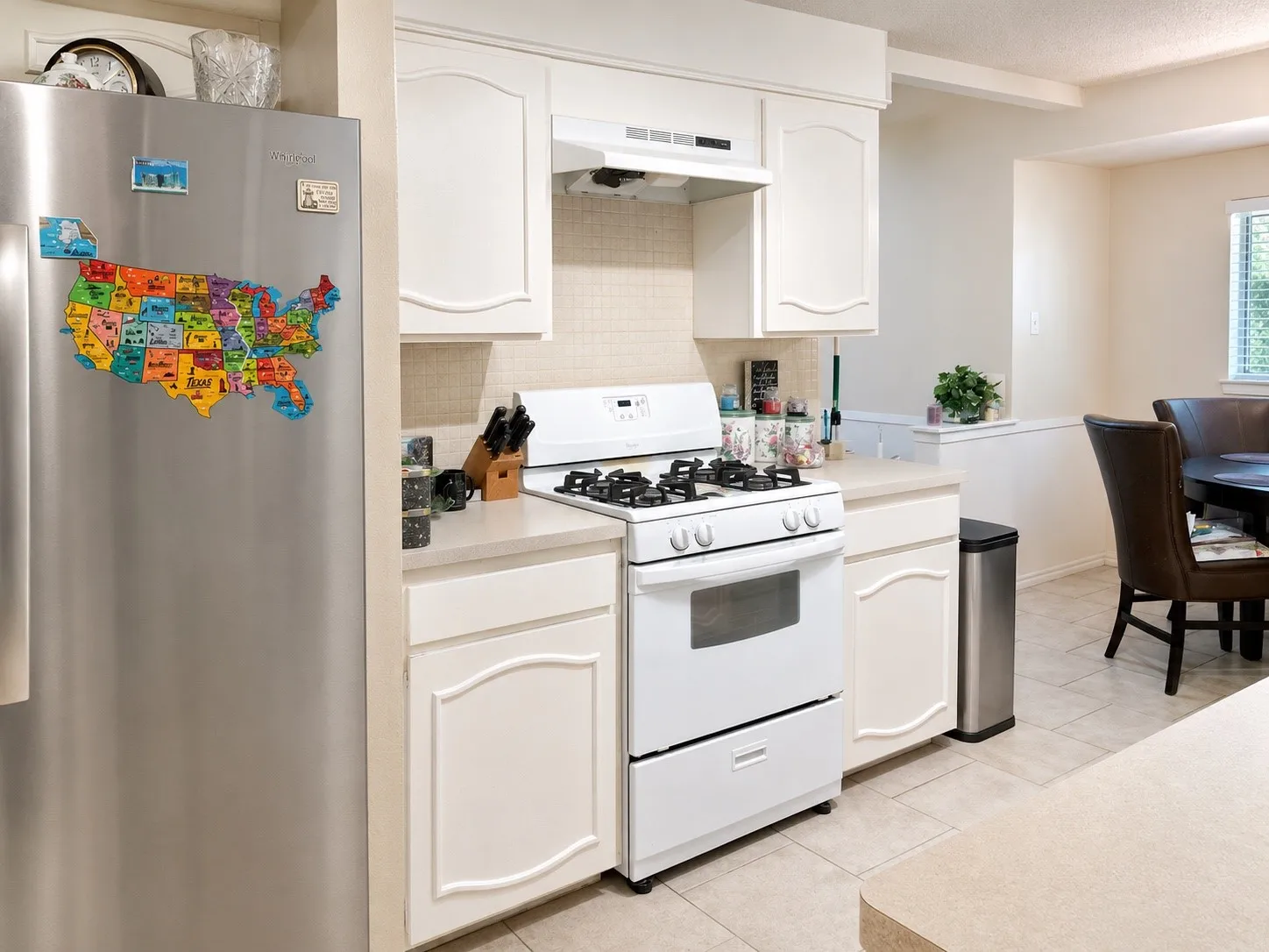 Kitchen featuring white cabinetry, white range, stainless steel refrigerator, and tiled backsplash