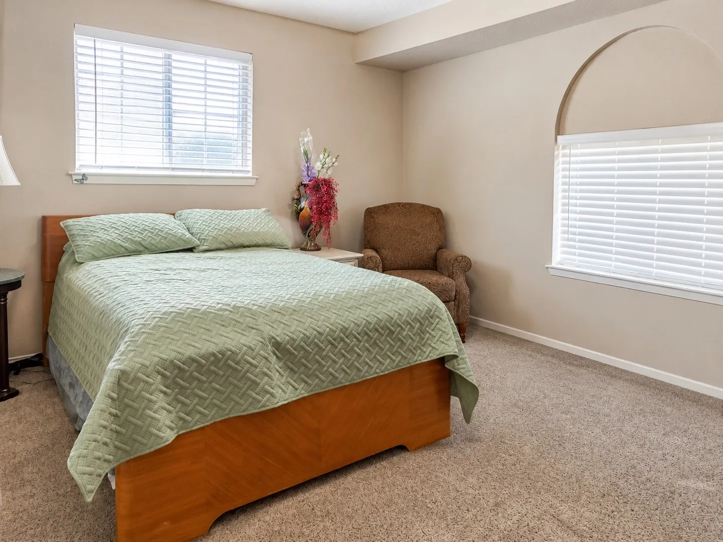 Carpeted room with a large window and an arched window, featuring a recessed ceiling element
