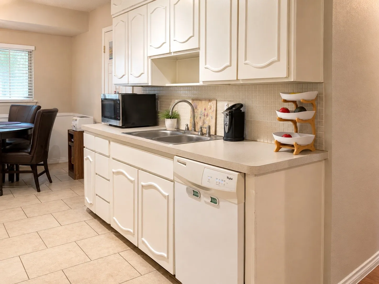 Kitchen featuring white cabinetry, light-toned countertops, a tile backsplash, and a built-in dishwasher