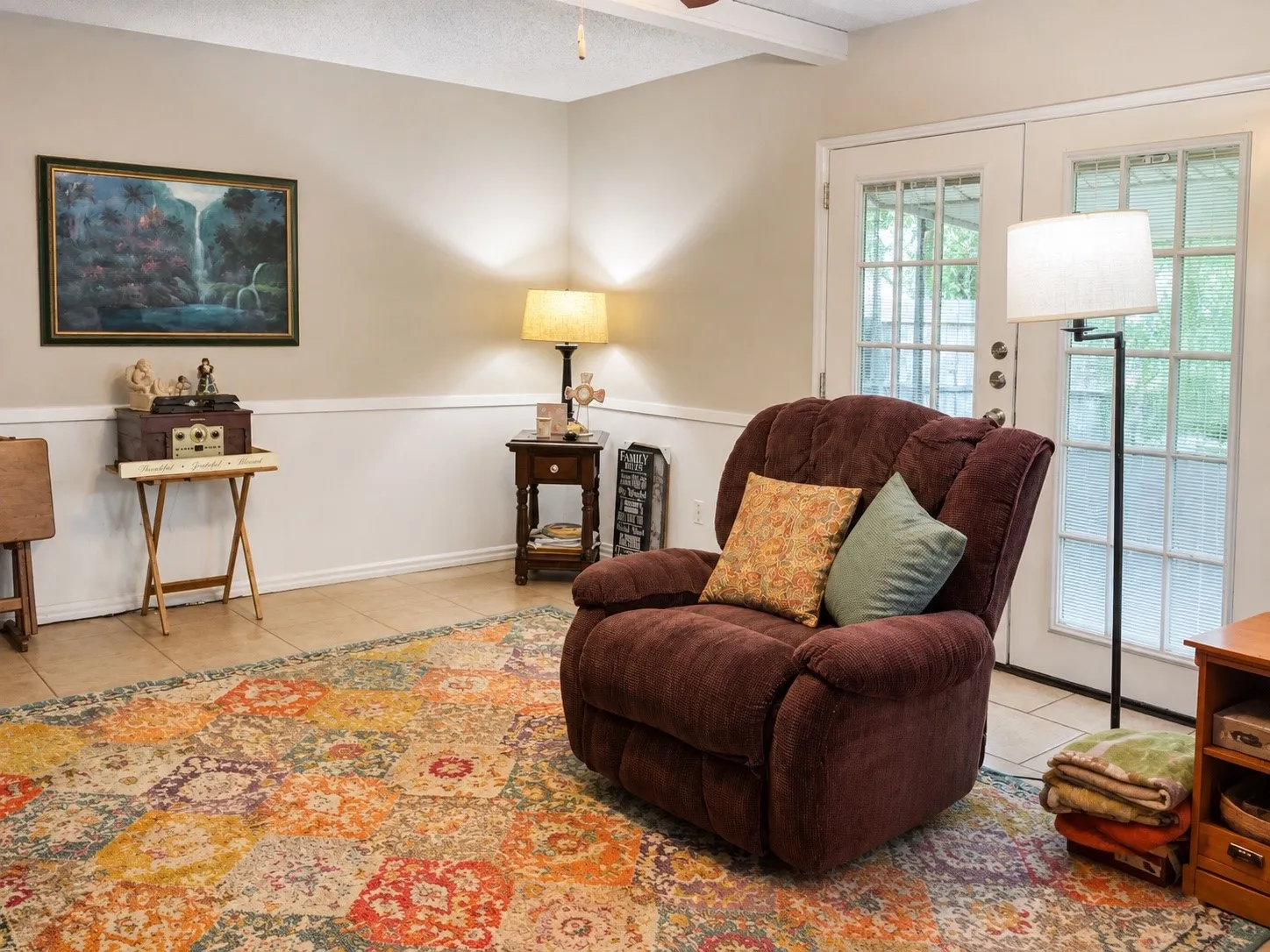 Tile flooring, French doors with divided lites, chair rail molding, ceiling fan, and painted ceiling beams