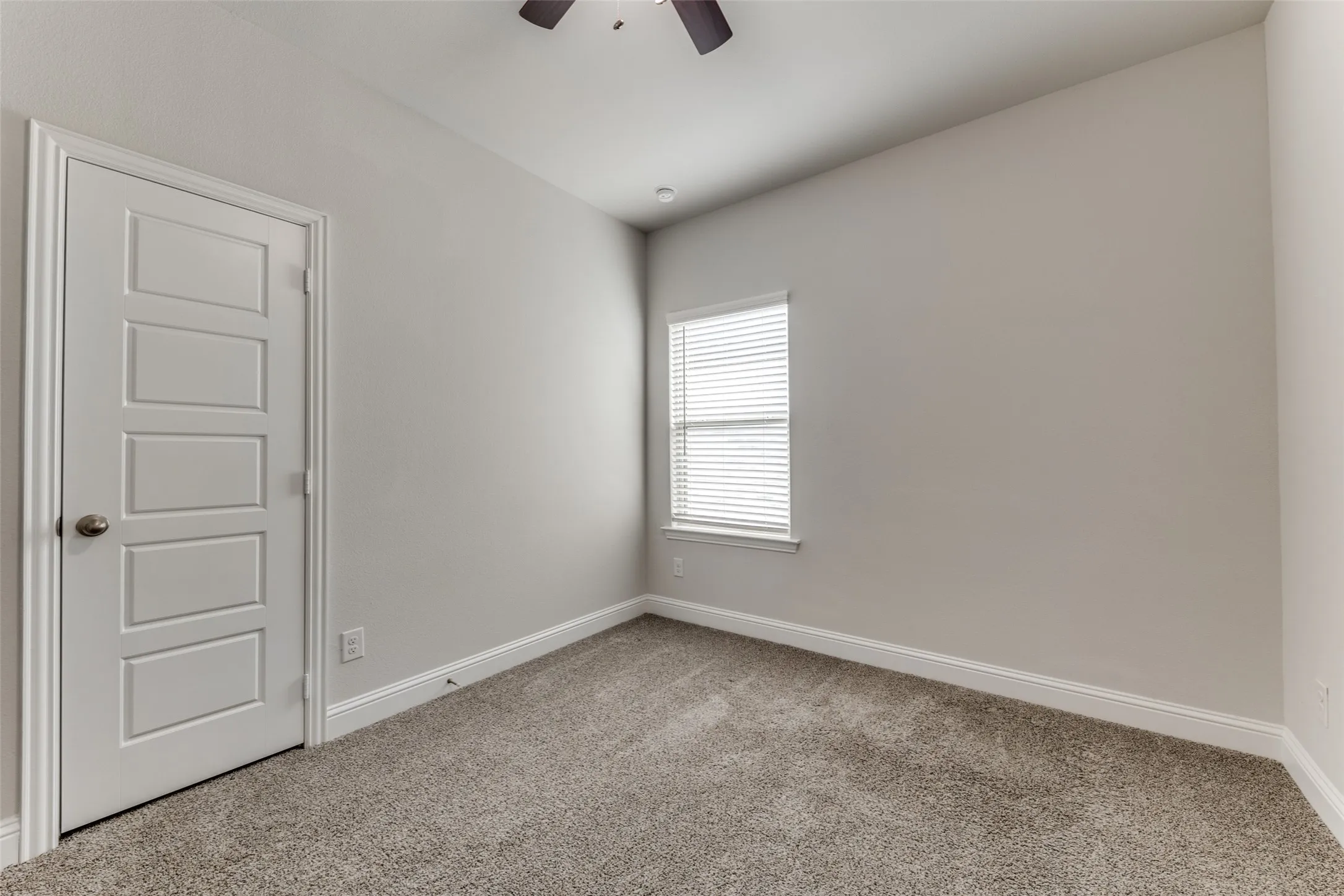 Carpeted spare room featuring a ceiling fan and baseboards