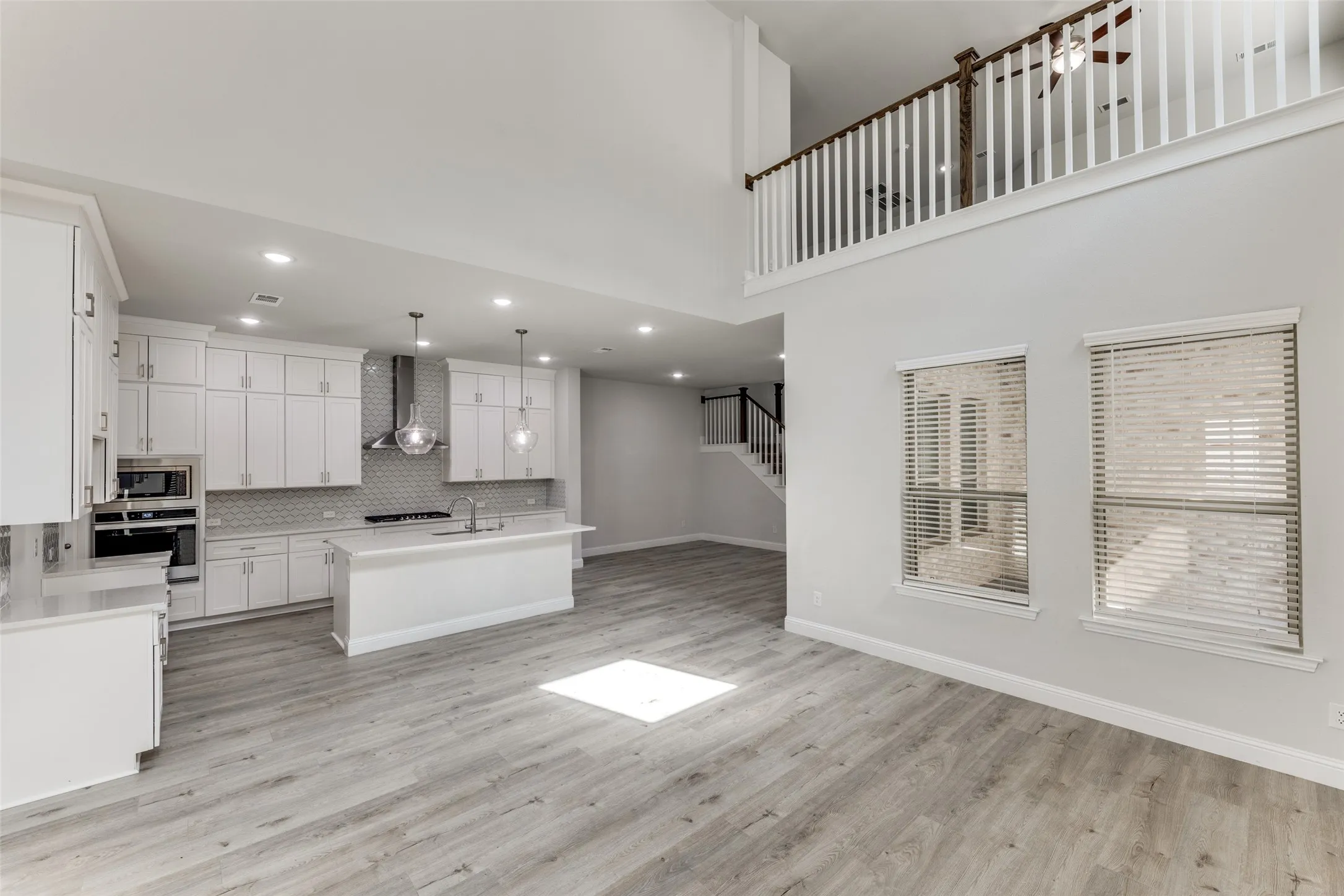 Kitchen with wall chimney exhaust hood, stainless steel appliances, a sink, decorative backsplash, and recessed lighting